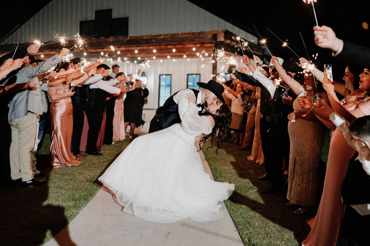 Wedding guests form a sparkler exit tunnel at night for the newlyweds on their special day.