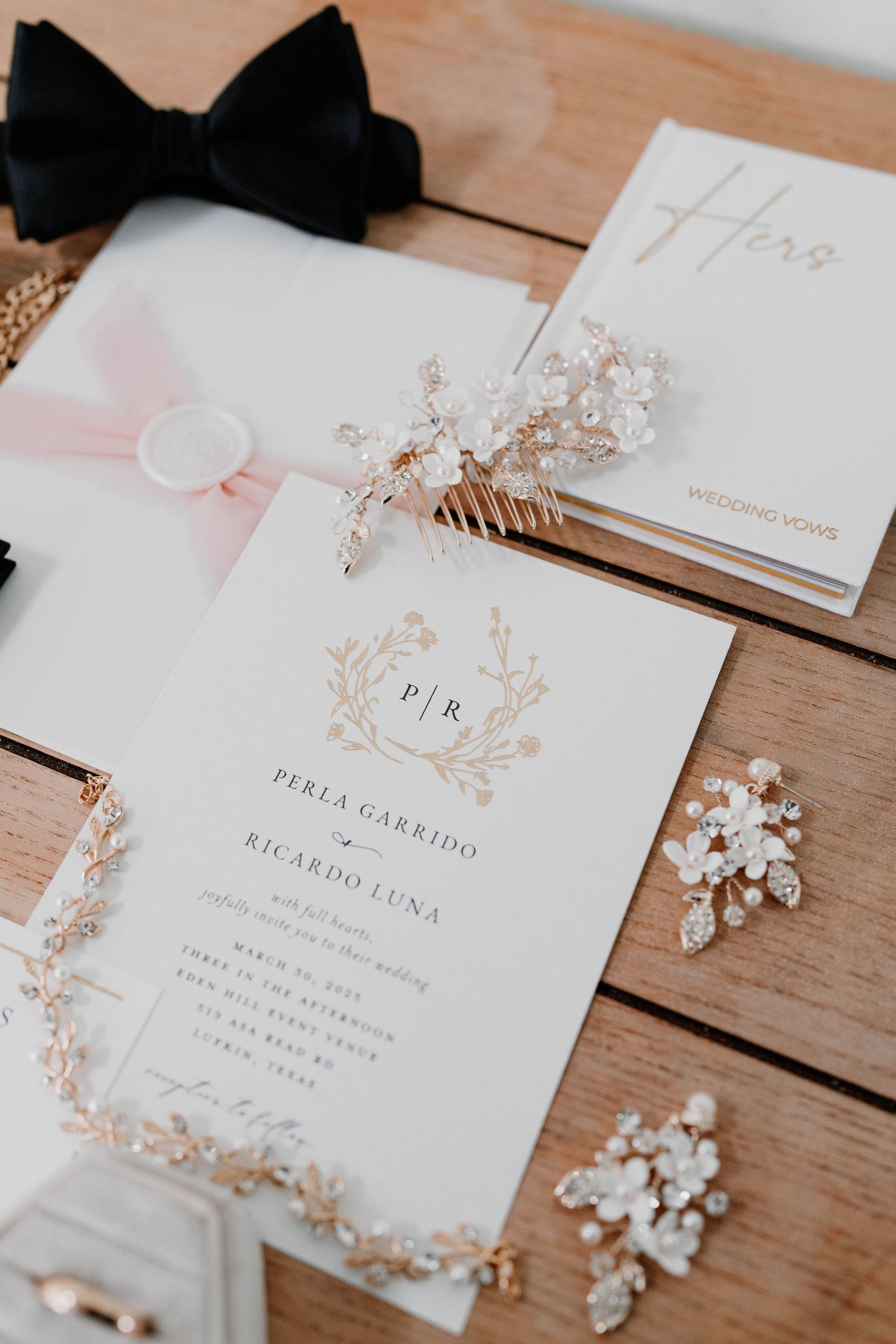 Wedding stationery set with delicate pearl accessories on wooden surface.