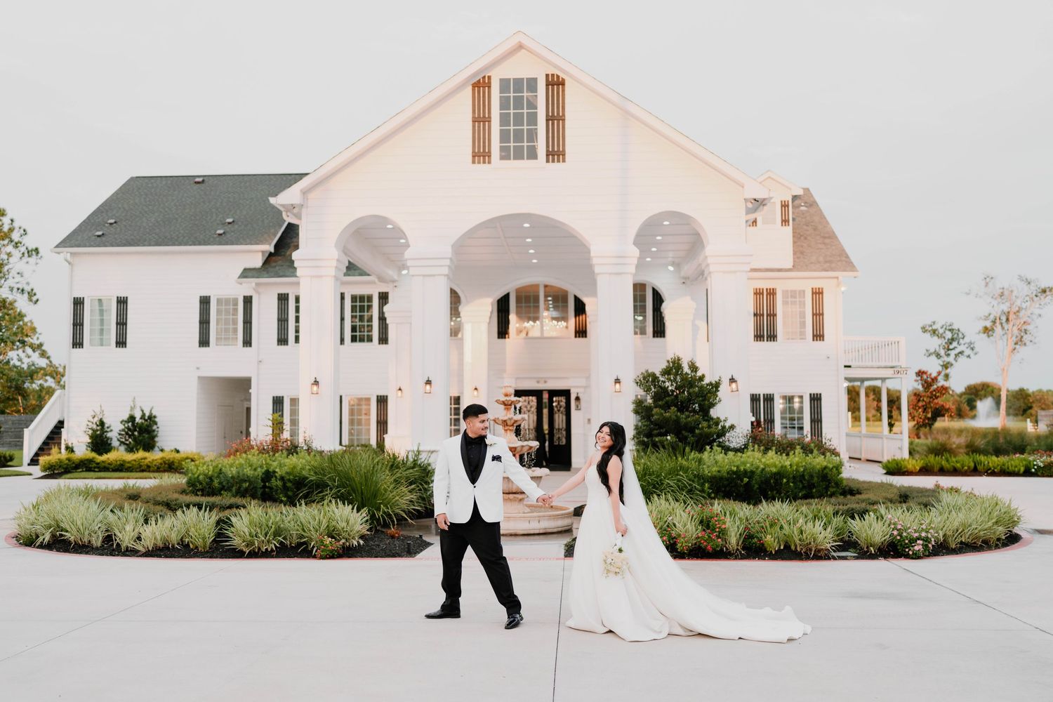 Elegant white wedding venue with classic architecture and manicured gardens.