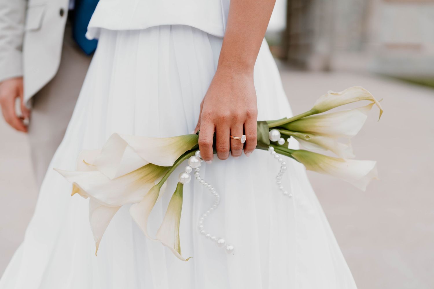 Detail shot of white calla lilies against flowing bridal dress fabric.