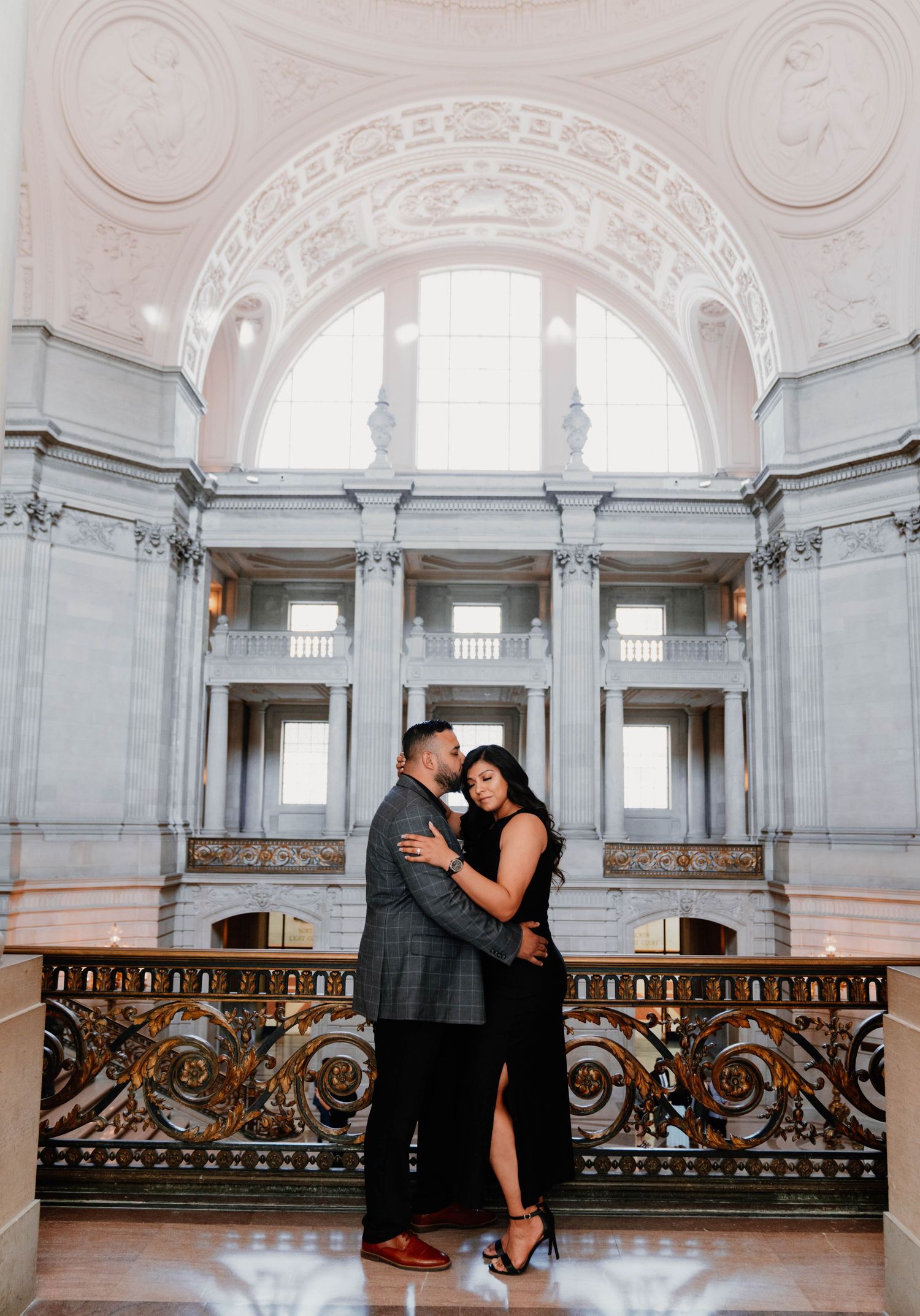 Romantic couple sharing intimate moments in a grand marble building interior.