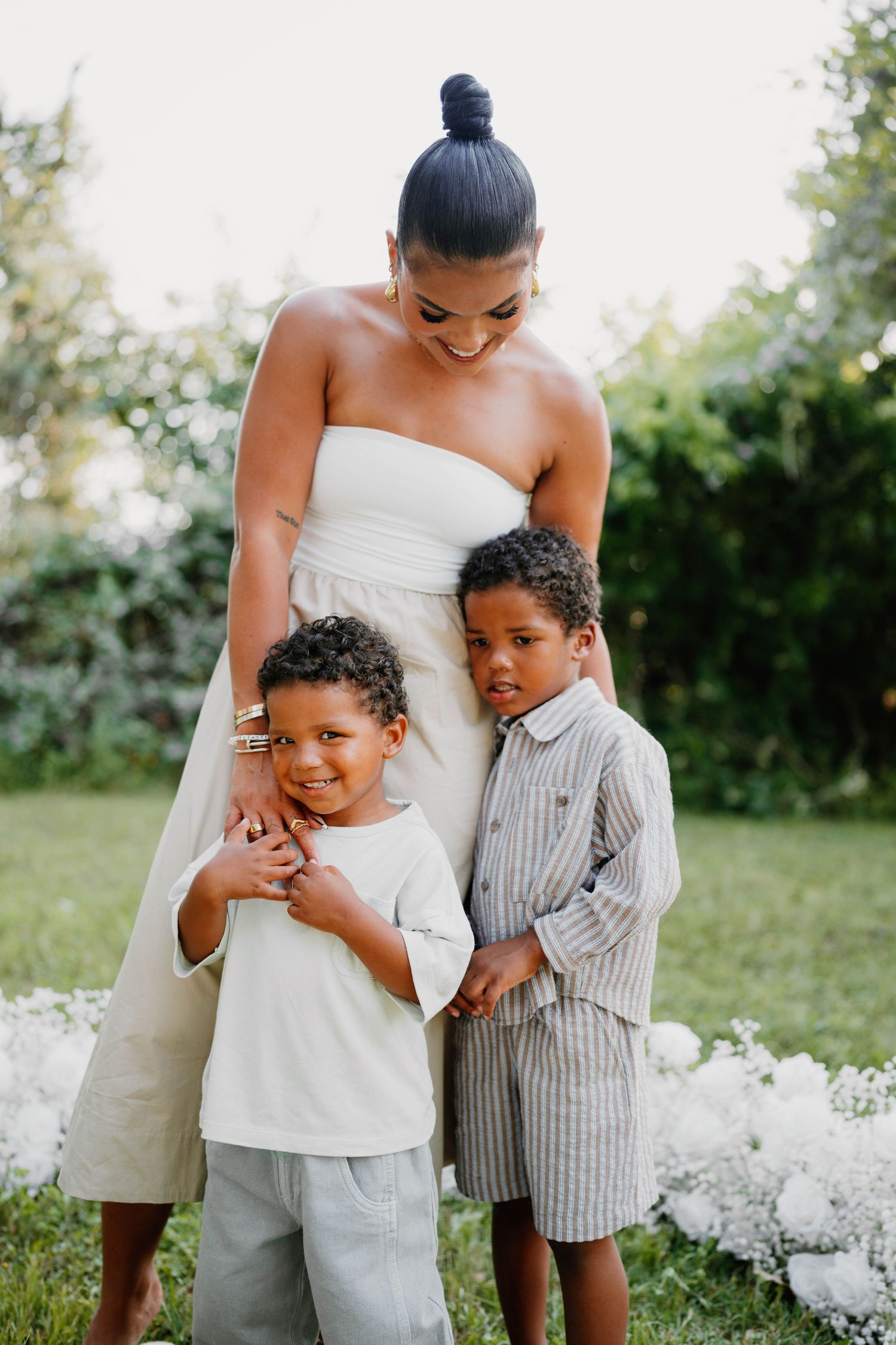 A heartwarming family embrace in a garden setting with white flowers and greenery.