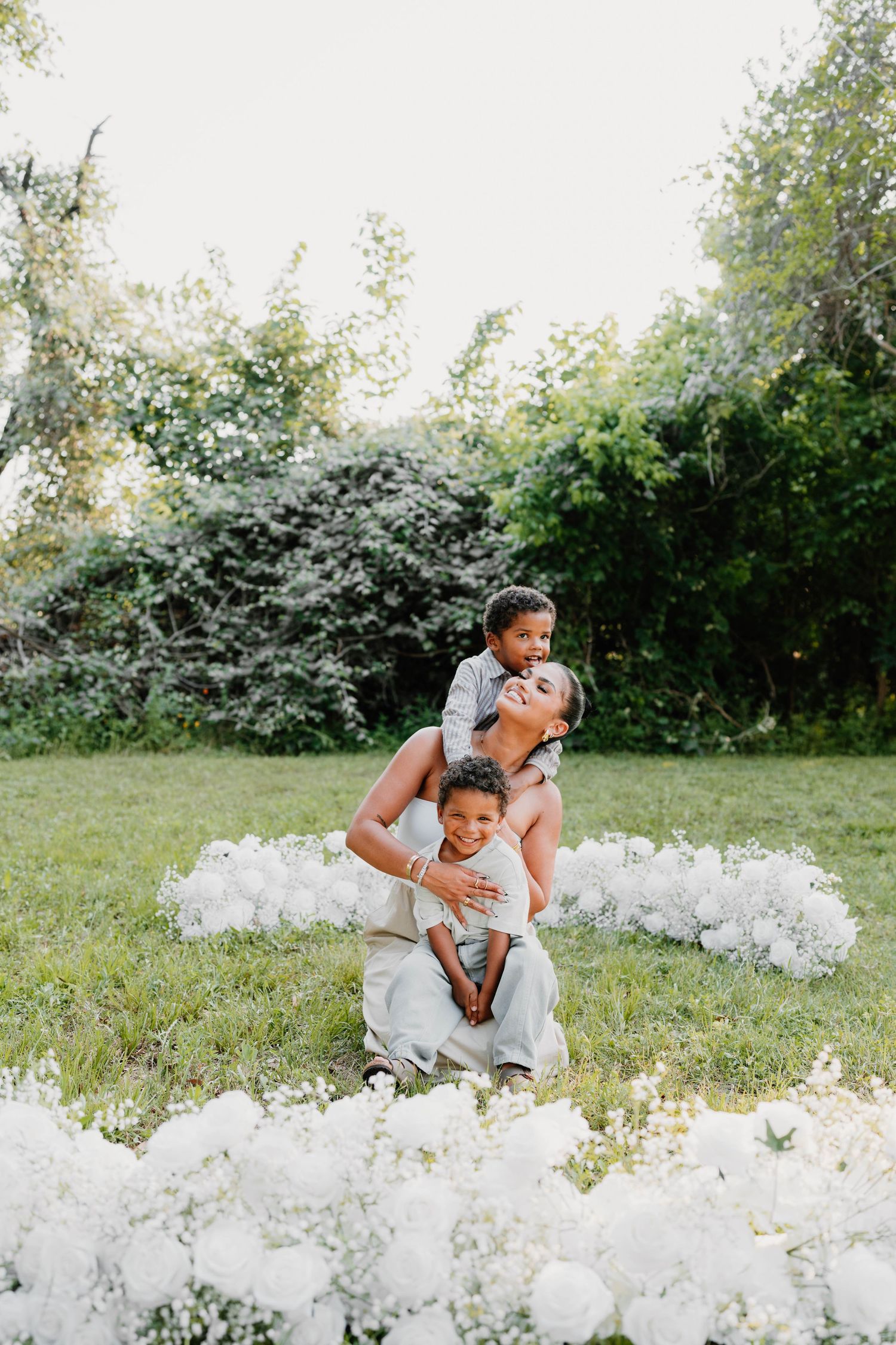 Family playfully poses together in a field of white flowers during an outdoor photo session.