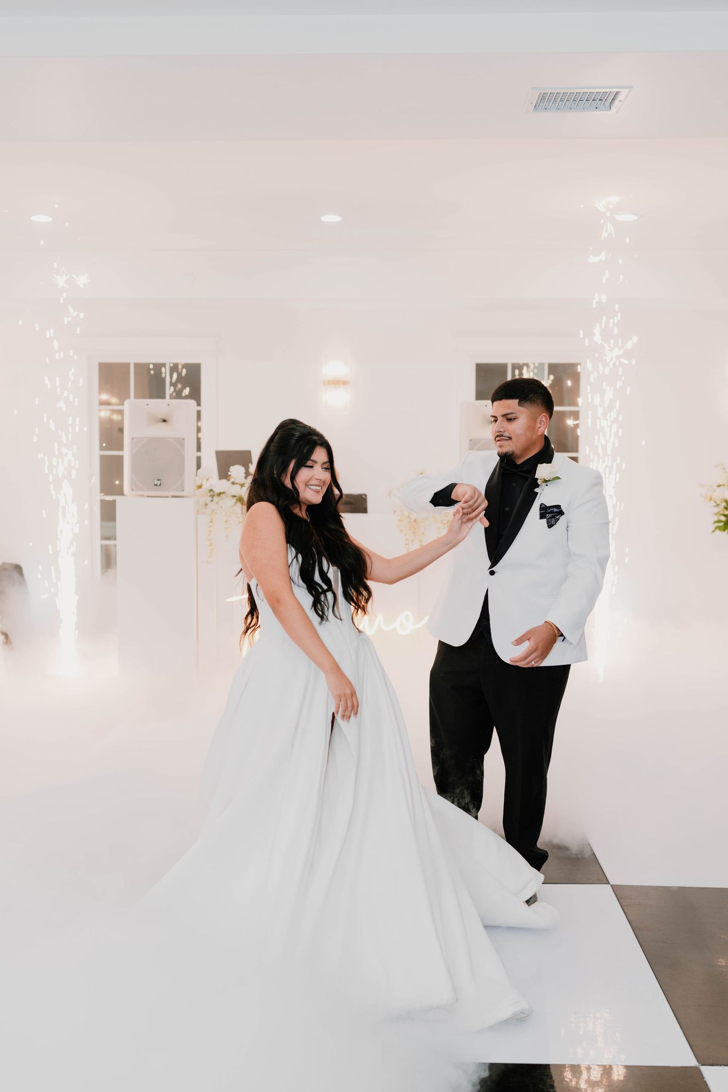 Playful dancing sequence of newlyweds in a bright white reception venue.
