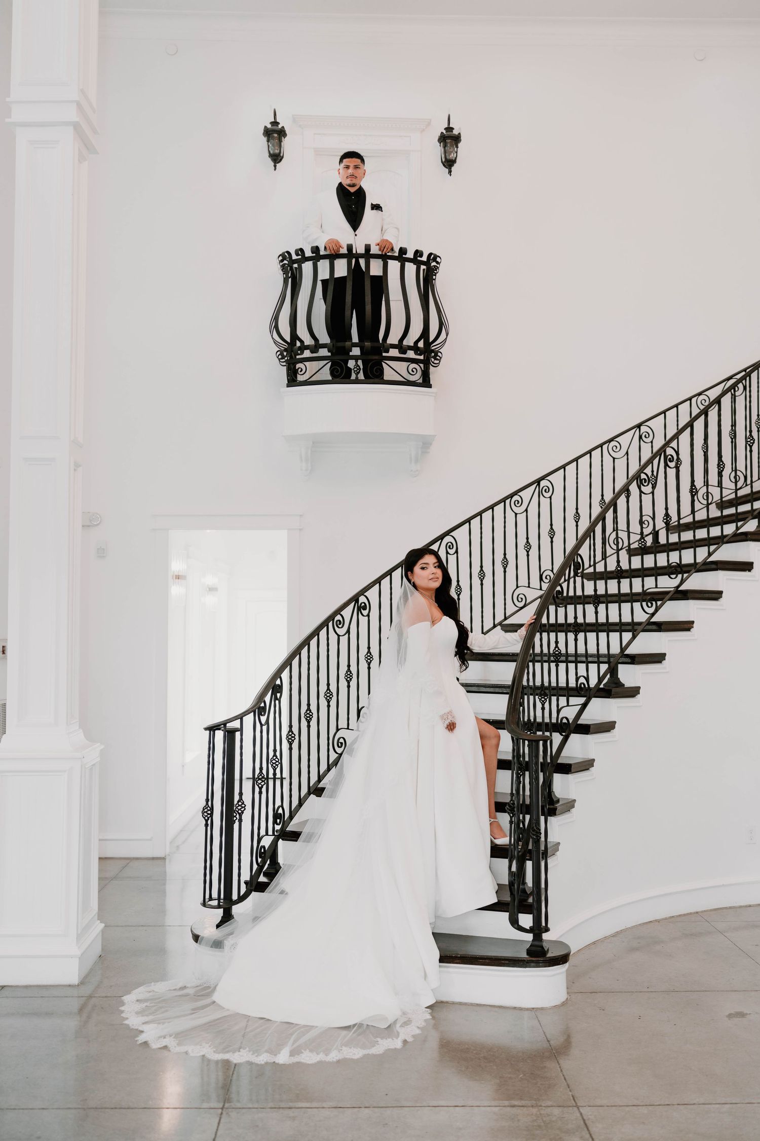 An elegant wedding venue interior featuring a grand spiral staircase with black railings.