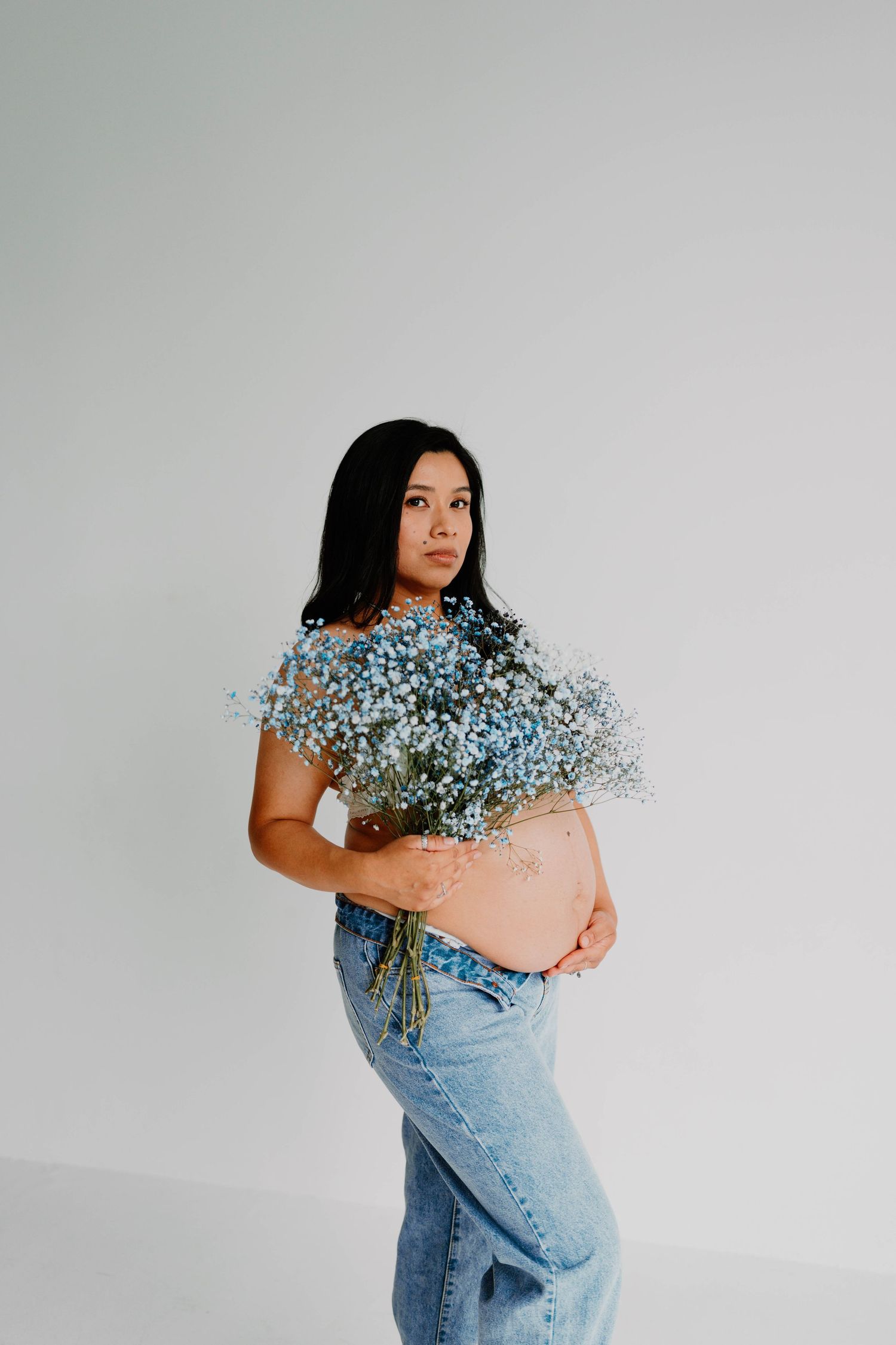 Artistic portrait series with blue baby's breath flowers against grey background.