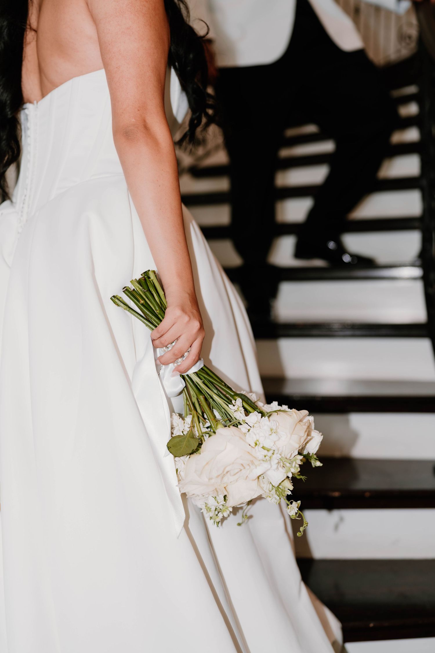 Close-up of bride holding elegant white floral bouquet against white dress.
