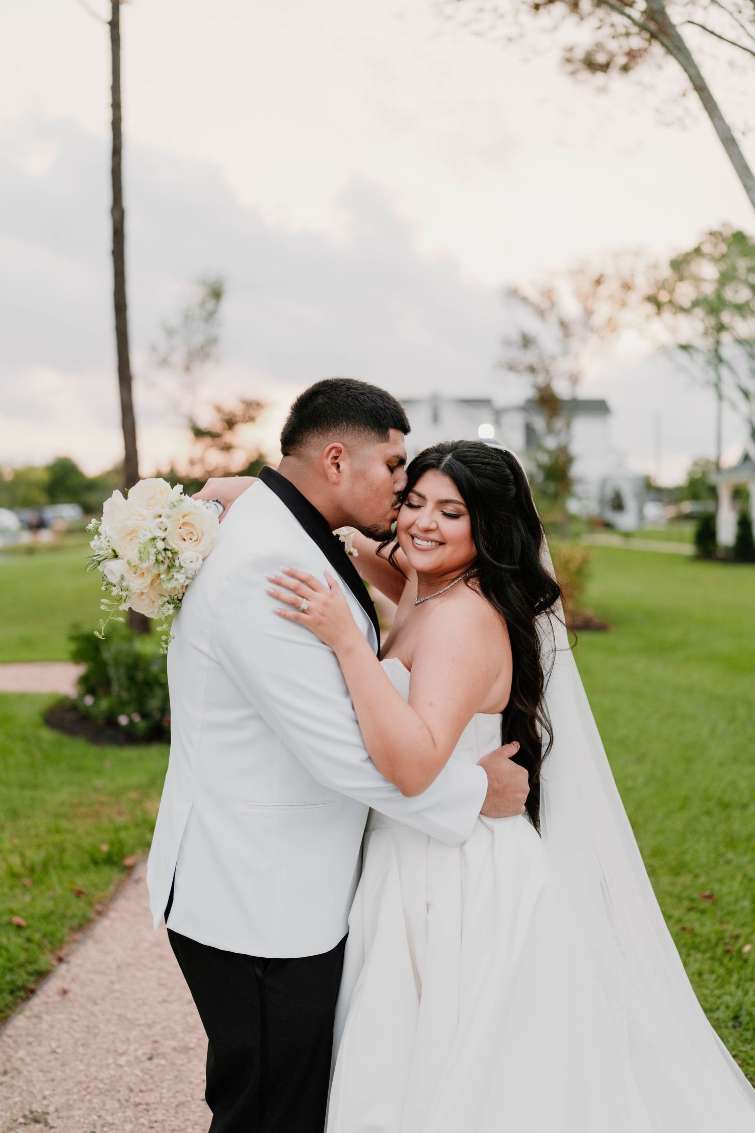 A romantic wedding photo shoot on a grassy lawn with white floral arrangements.