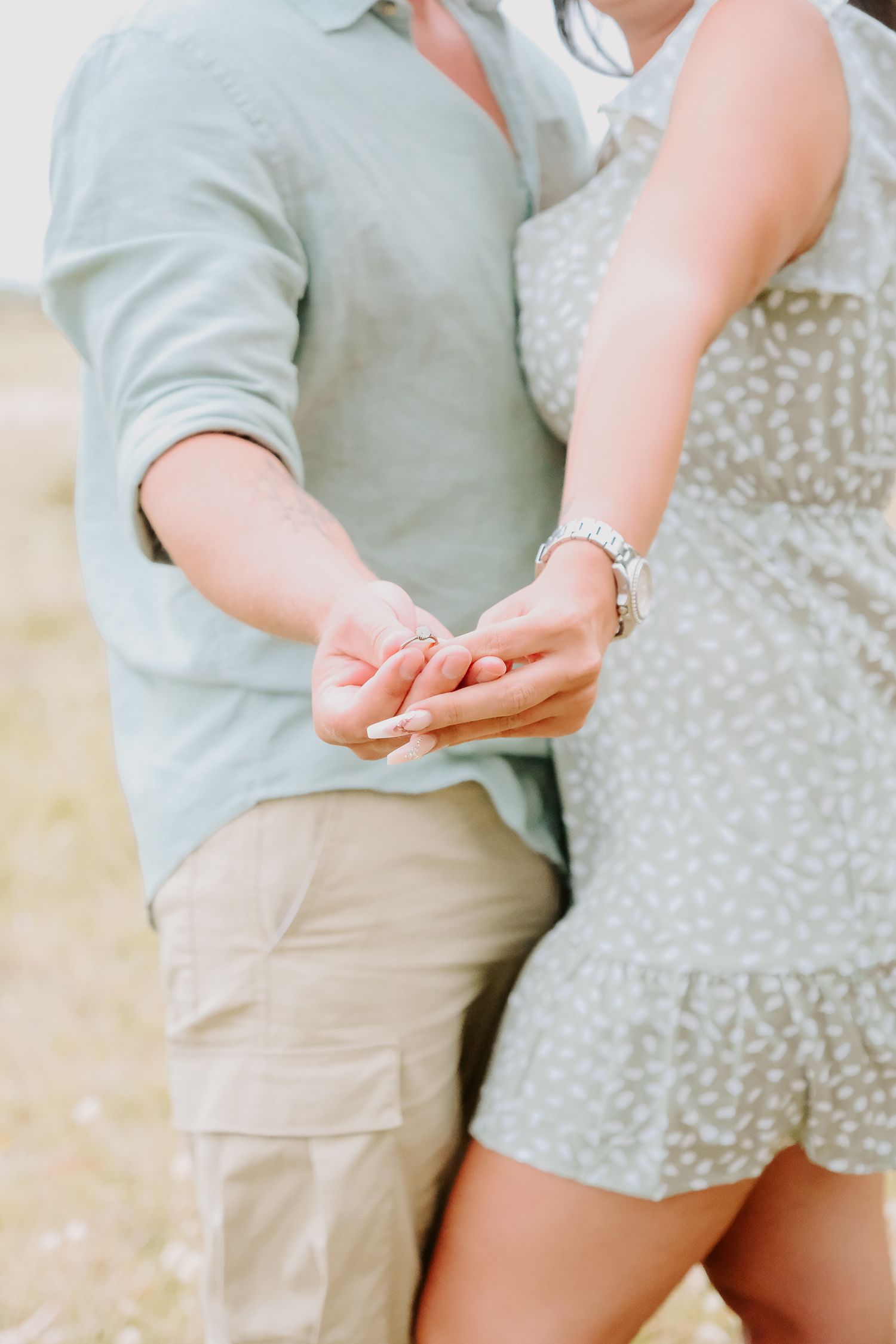 A close-up shot of two people holding hands outdoors in casual summer attire.