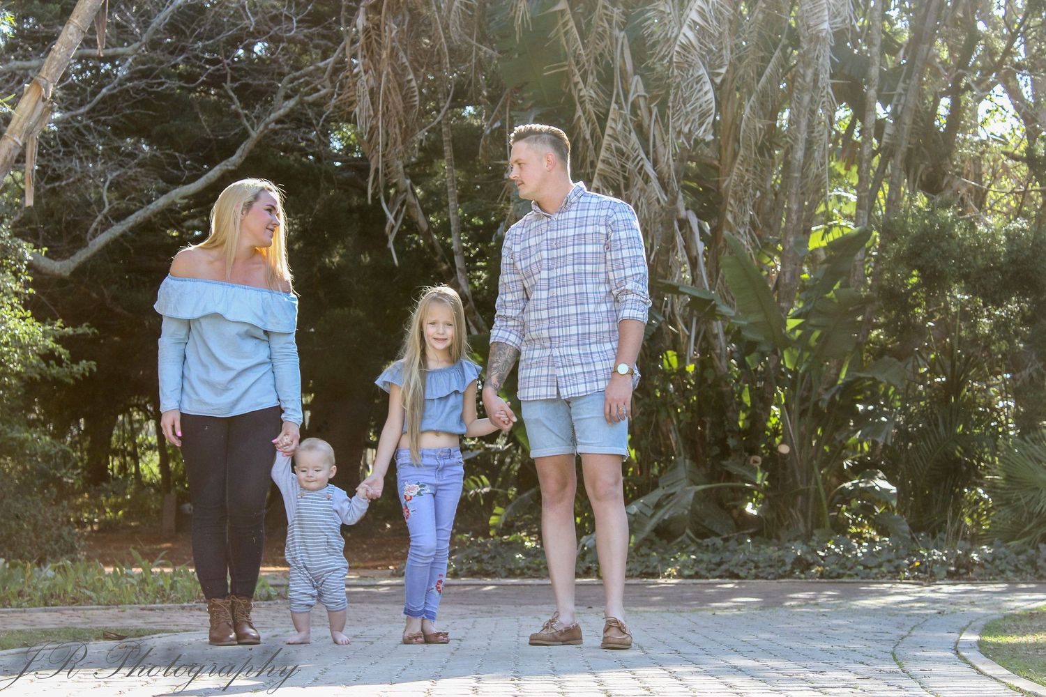 Family walking together on path through wooded area.