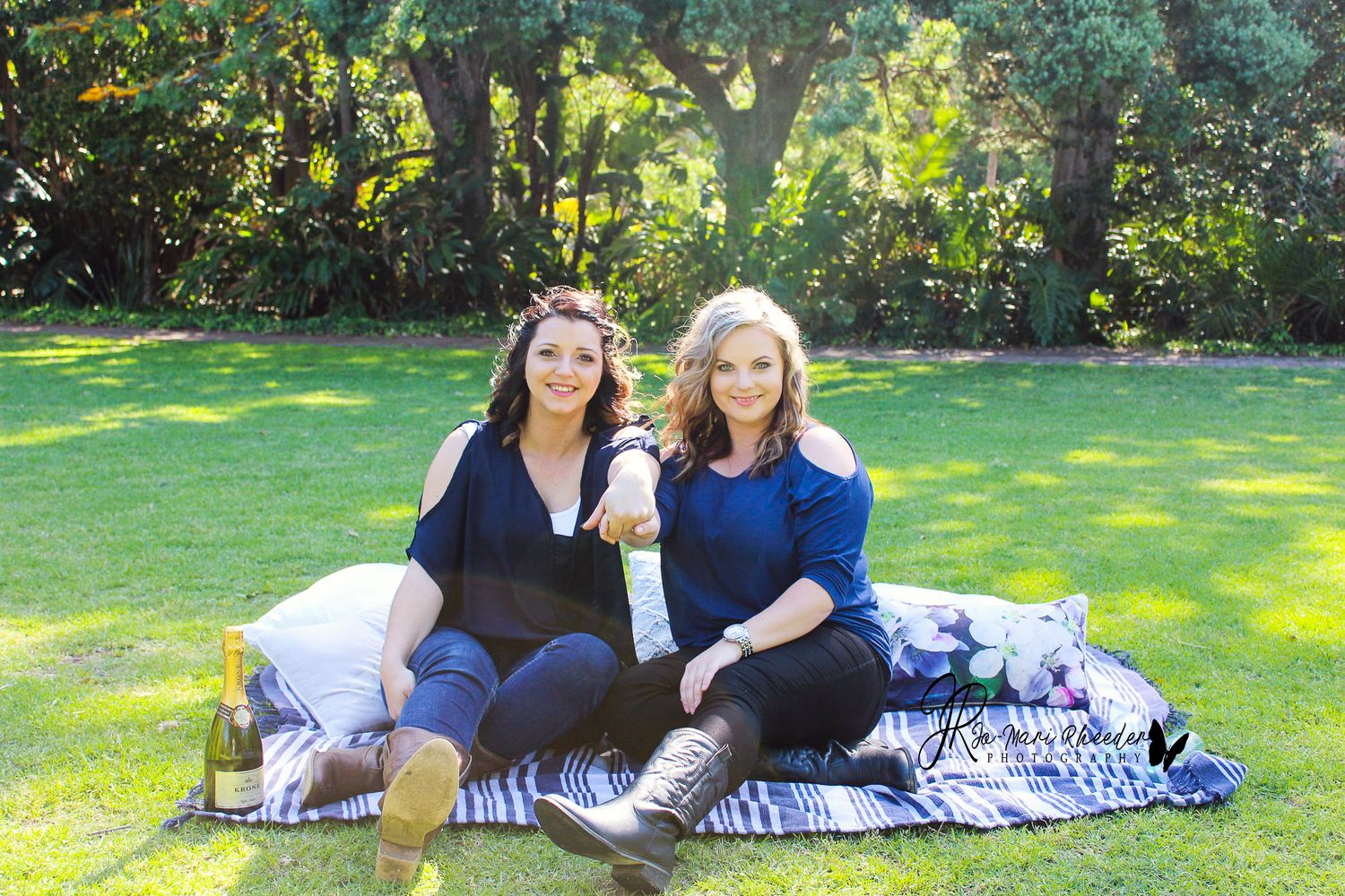 Two friends relaxing on a blanket in a sunny garden setting.