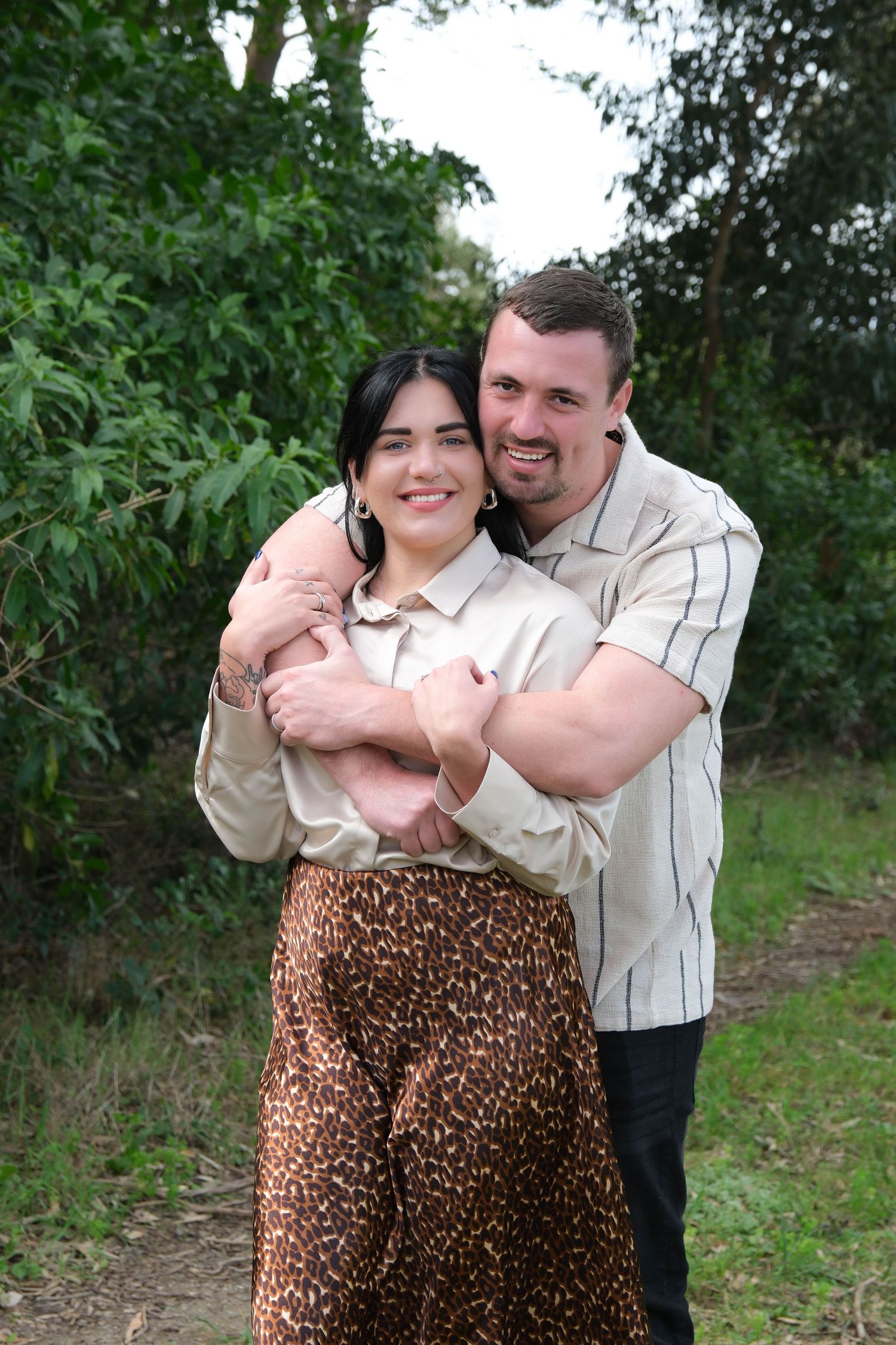Affectionate moment captured on woodland path with natural green backdrop.