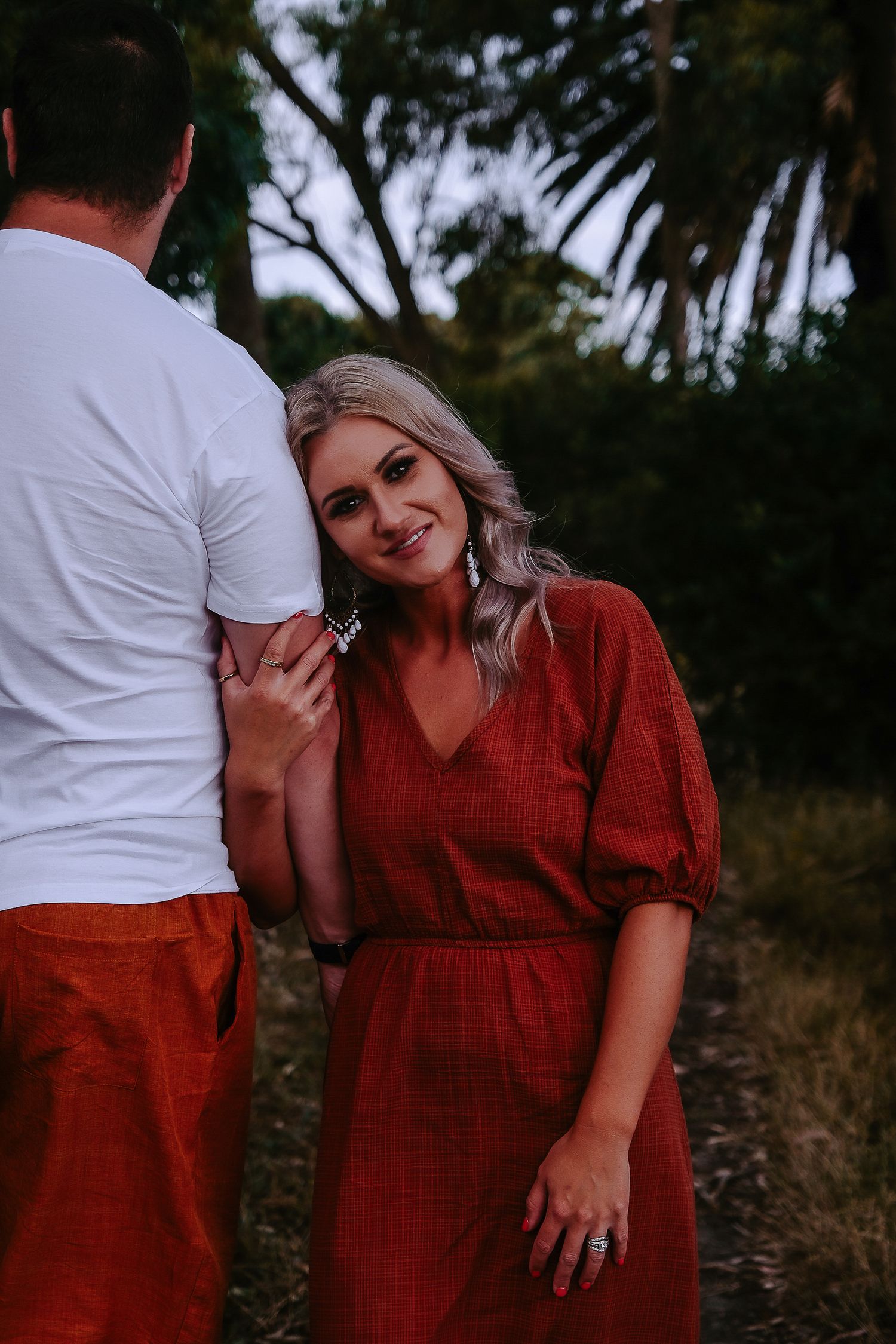 Couple shares romantic moment in outdoor setting wearing matching colors.