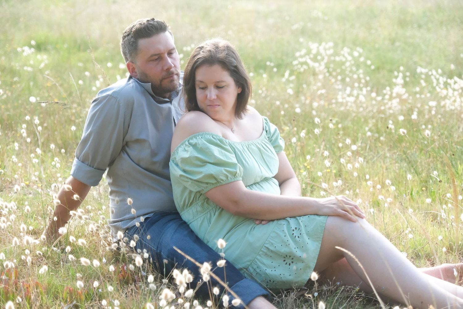 Couple sitting together in a sunny wildflower meadow.