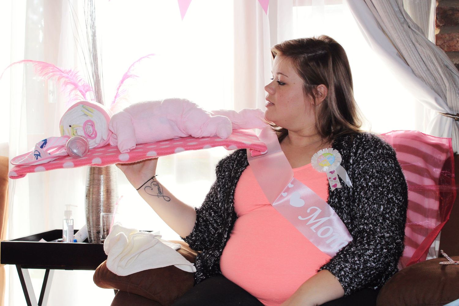 A feminine figure in black and pink sits in a bedroom decorated with pink and white accents and curtains.
