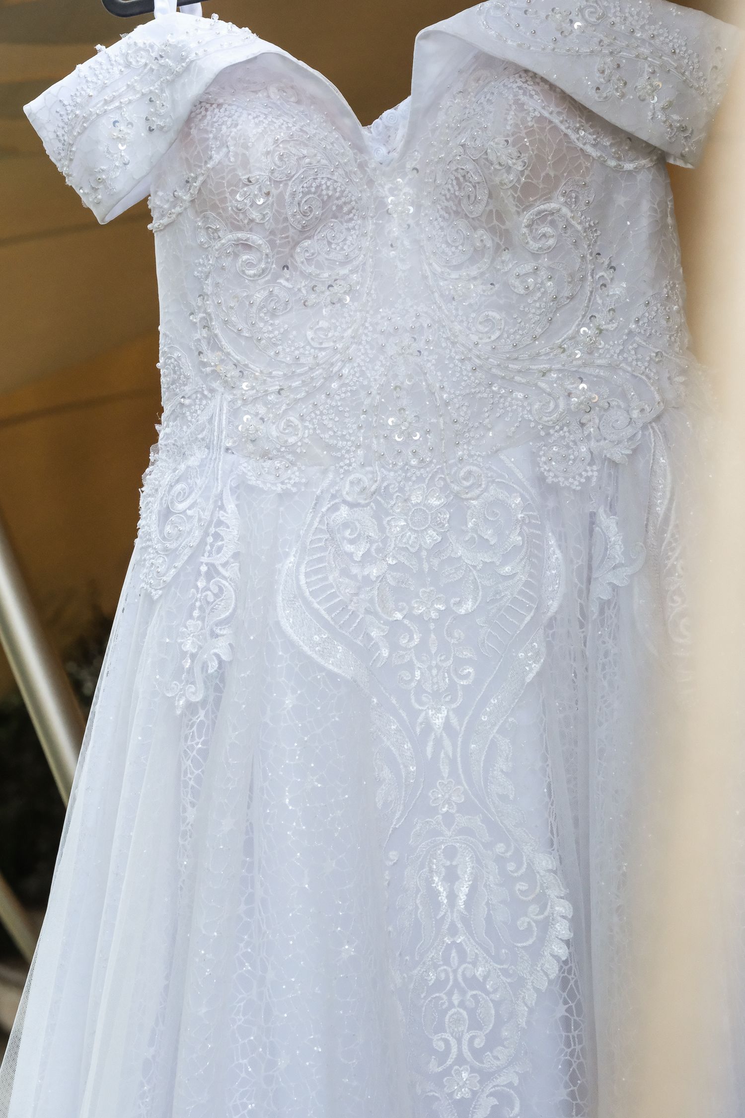 Close-up of an ornate white wedding dress bodice with lace and beaded details.