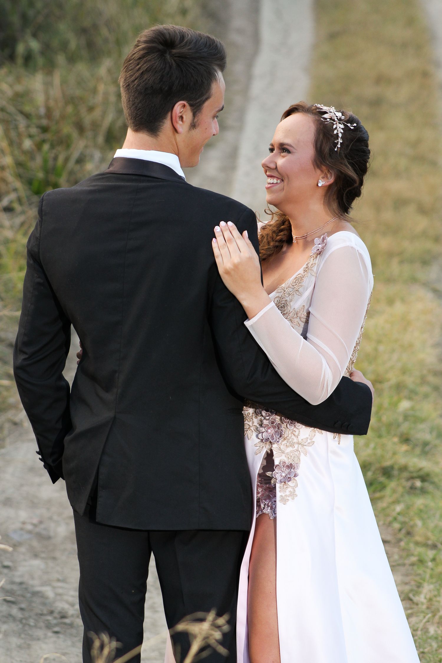 A couple shares a romantic outdoor moment in formal wedding attire.