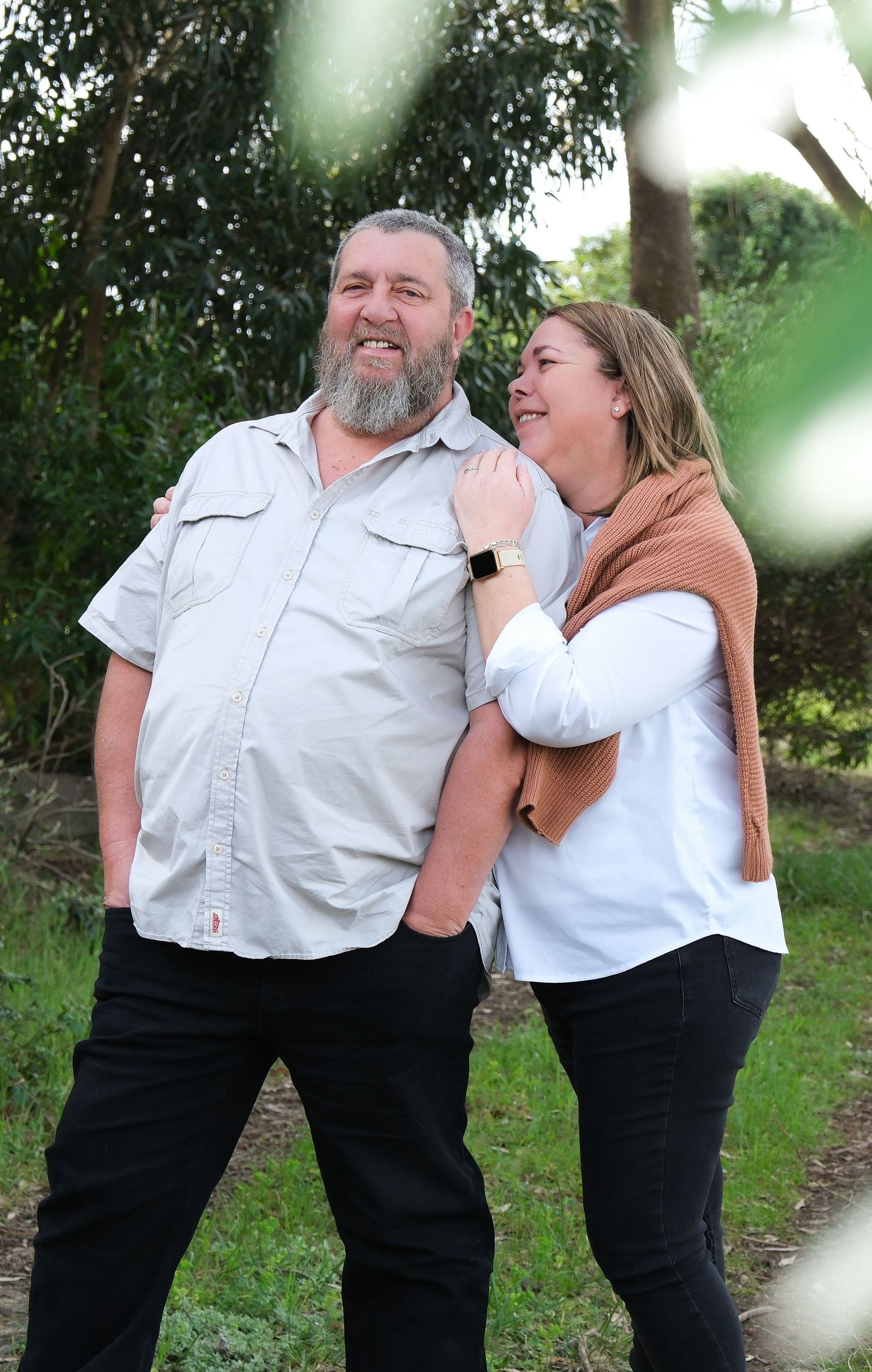 A couple sharing a joyful moment together on a tree-lined path.