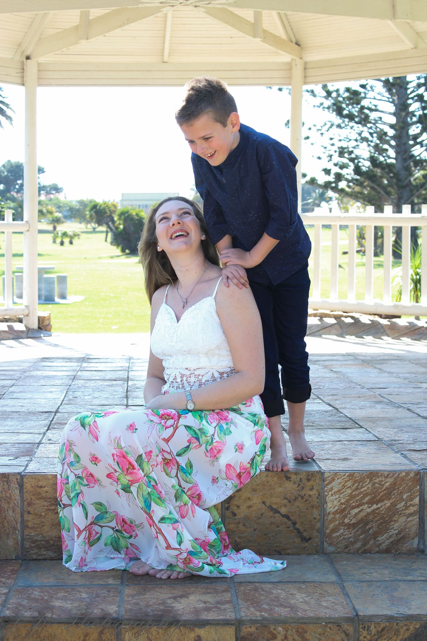 Sweet moment captured under a white gazebo with floral dress and casual attire.