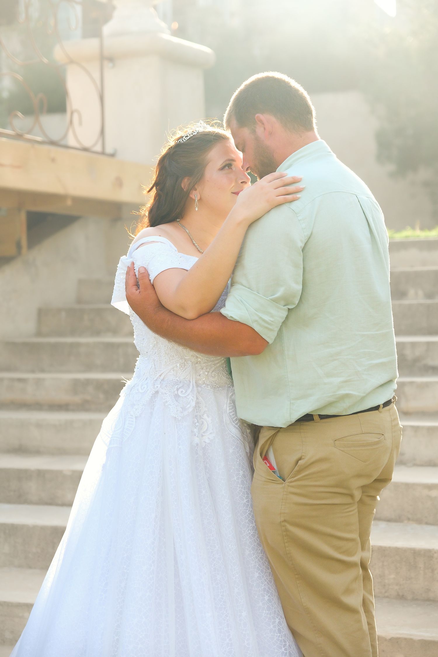 A tender moment between newlyweds on outdoor steps at sunset.