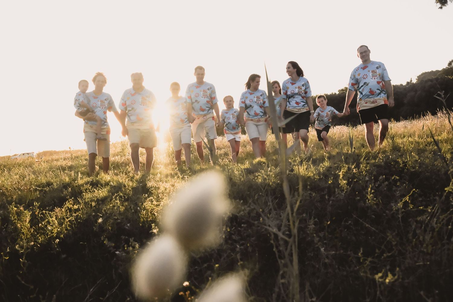 A group walks along a hillside path at sunset creating silhouettes against the golden sky.