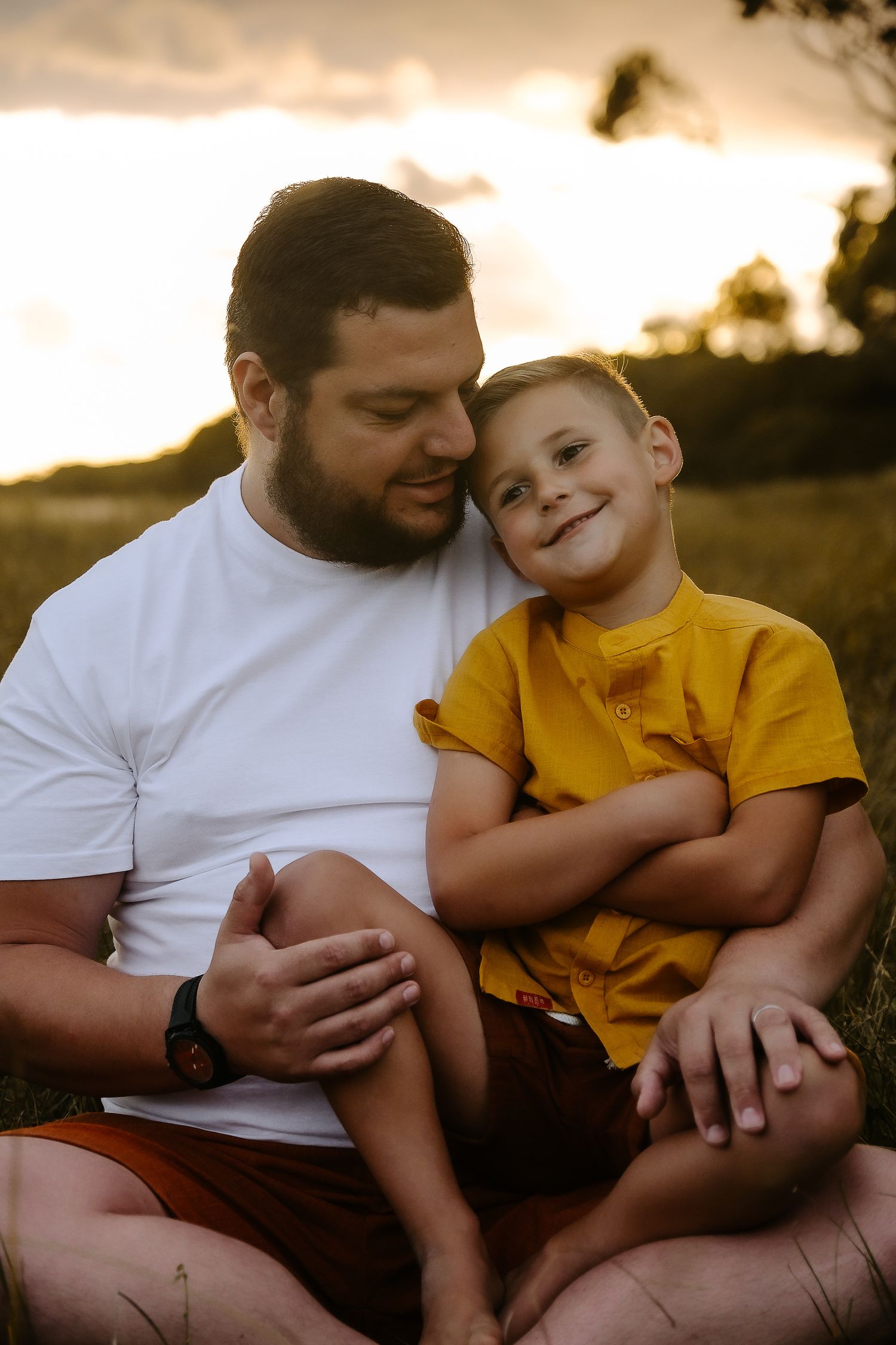 Parent and child sharing a warm moment together in a field at sunset.