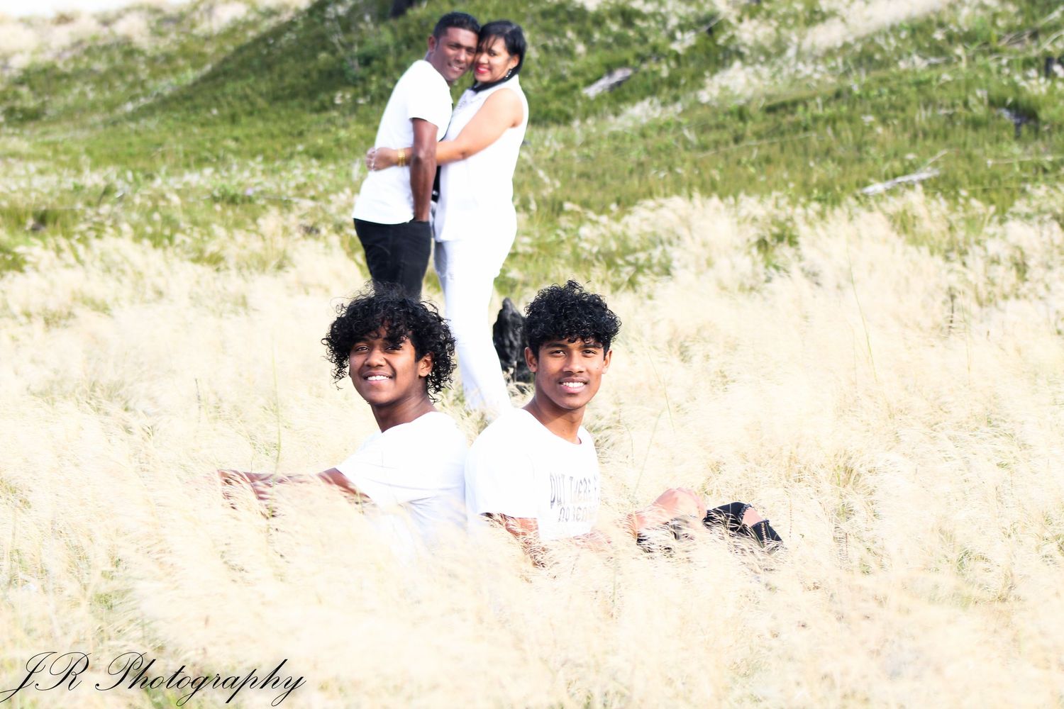 Fun beach portrait with people posing in tall grass against sunny coastal backdrop.