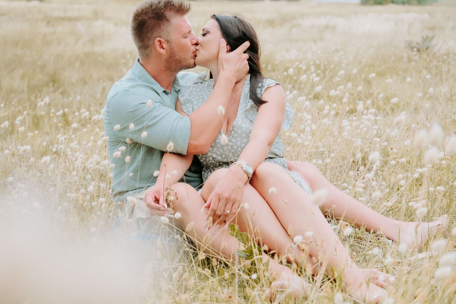 Romantic couple sharing tender moment while sitting in a wildflower meadow at sunset.