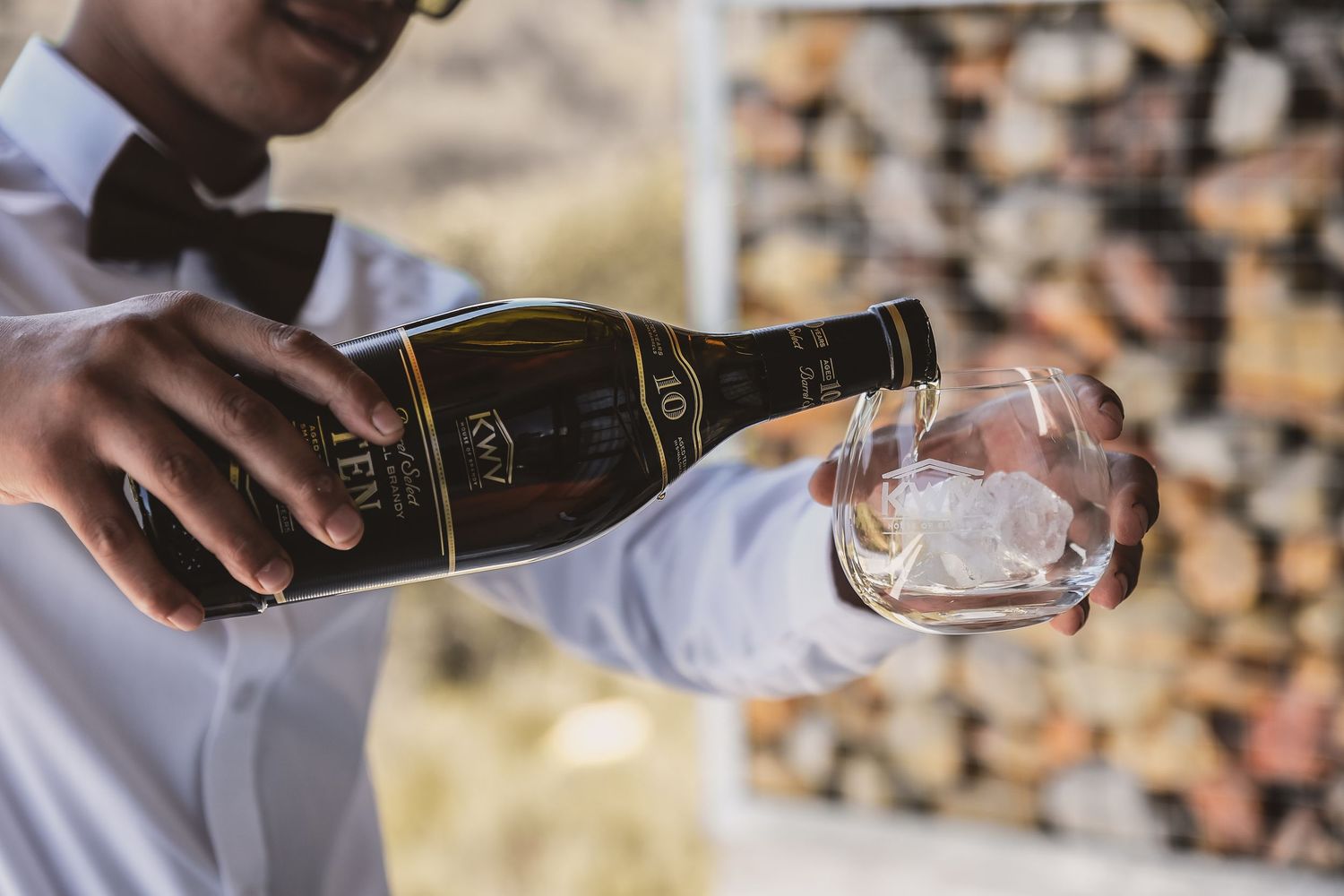 Close-up shot of wine being poured into a glass in natural lighting.