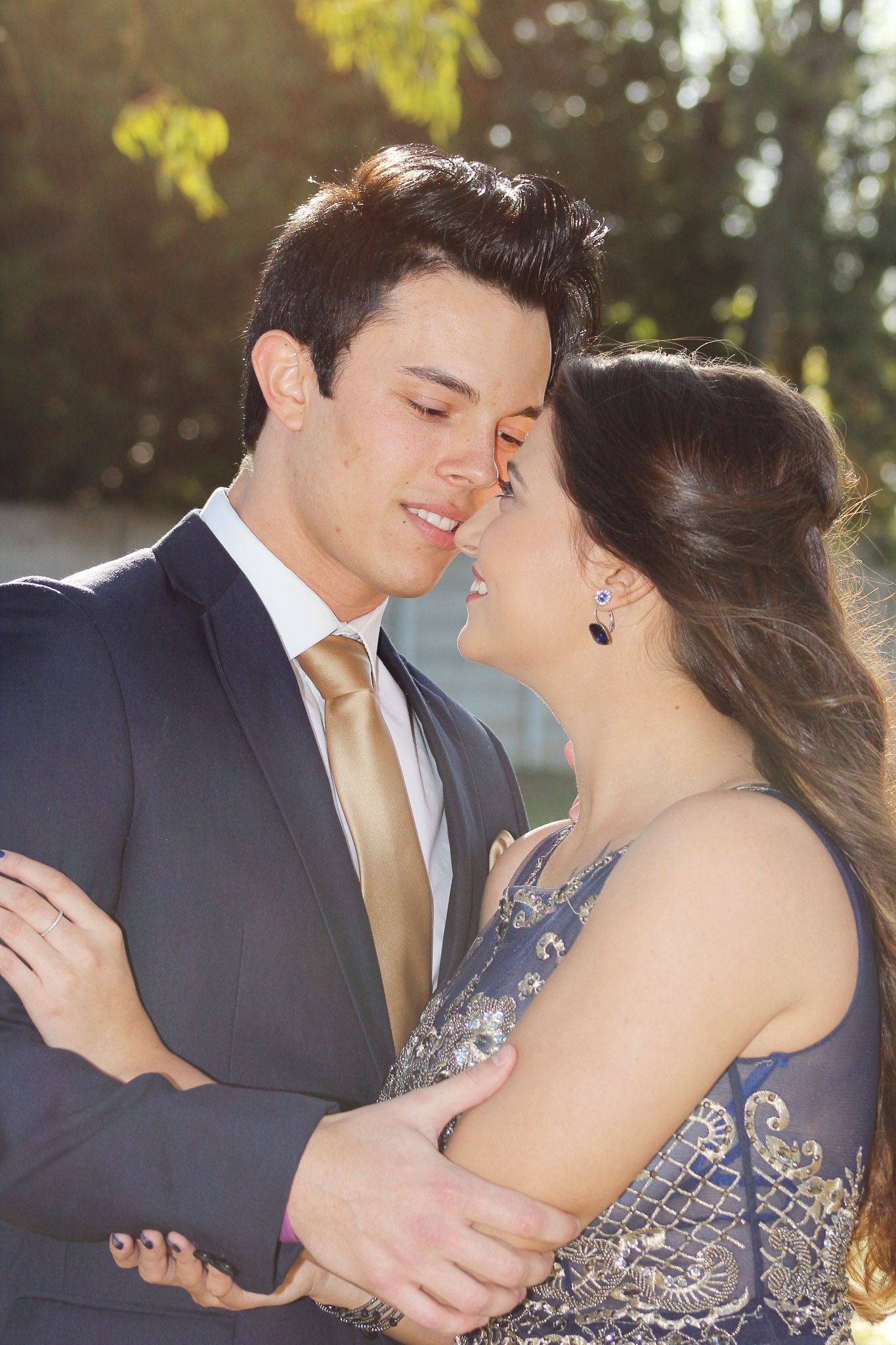 A couple shares an intimate moment in formal attire during a golden hour photoshoot.