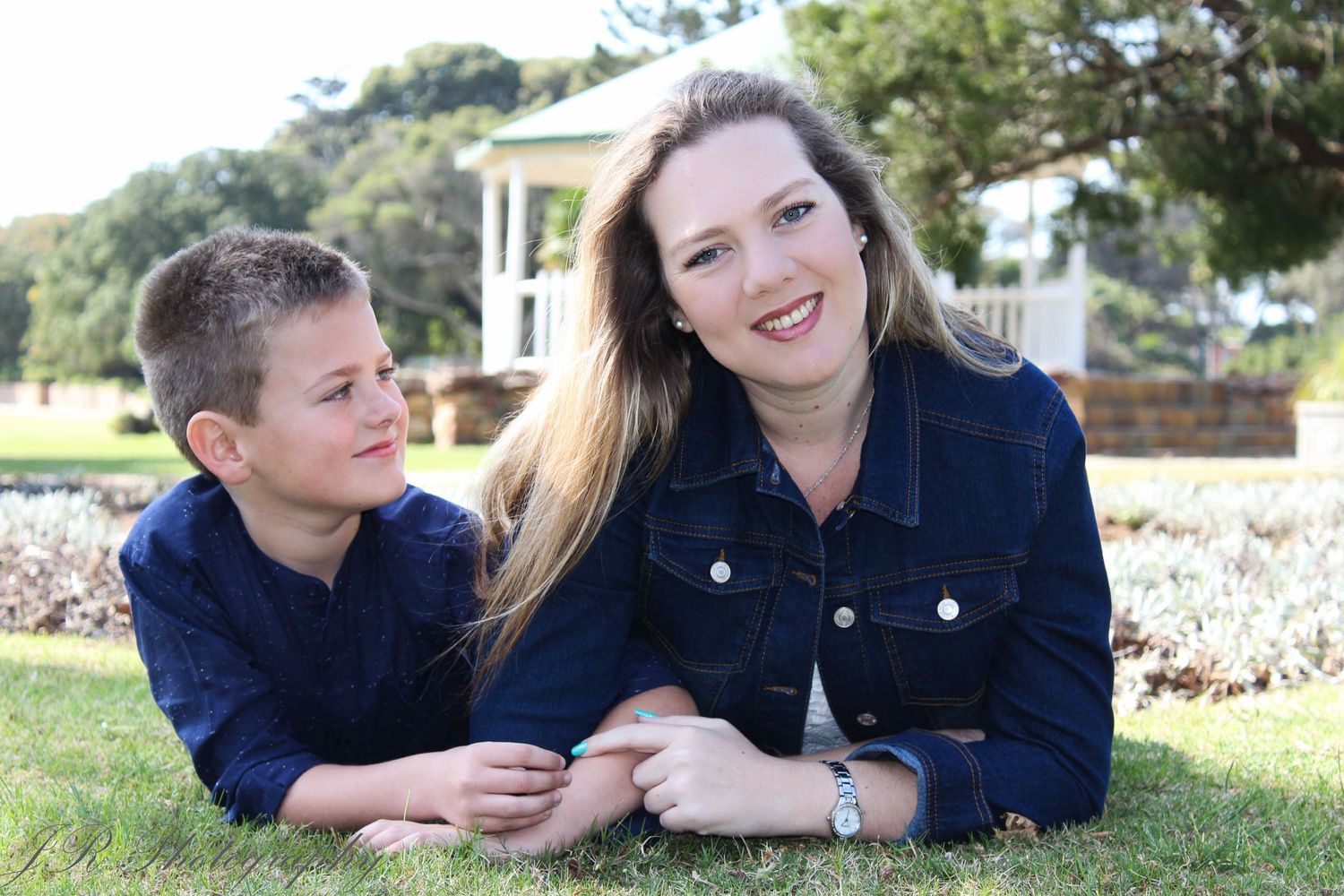 Casual outdoor portrait taken while laying on grass with house visible in background.