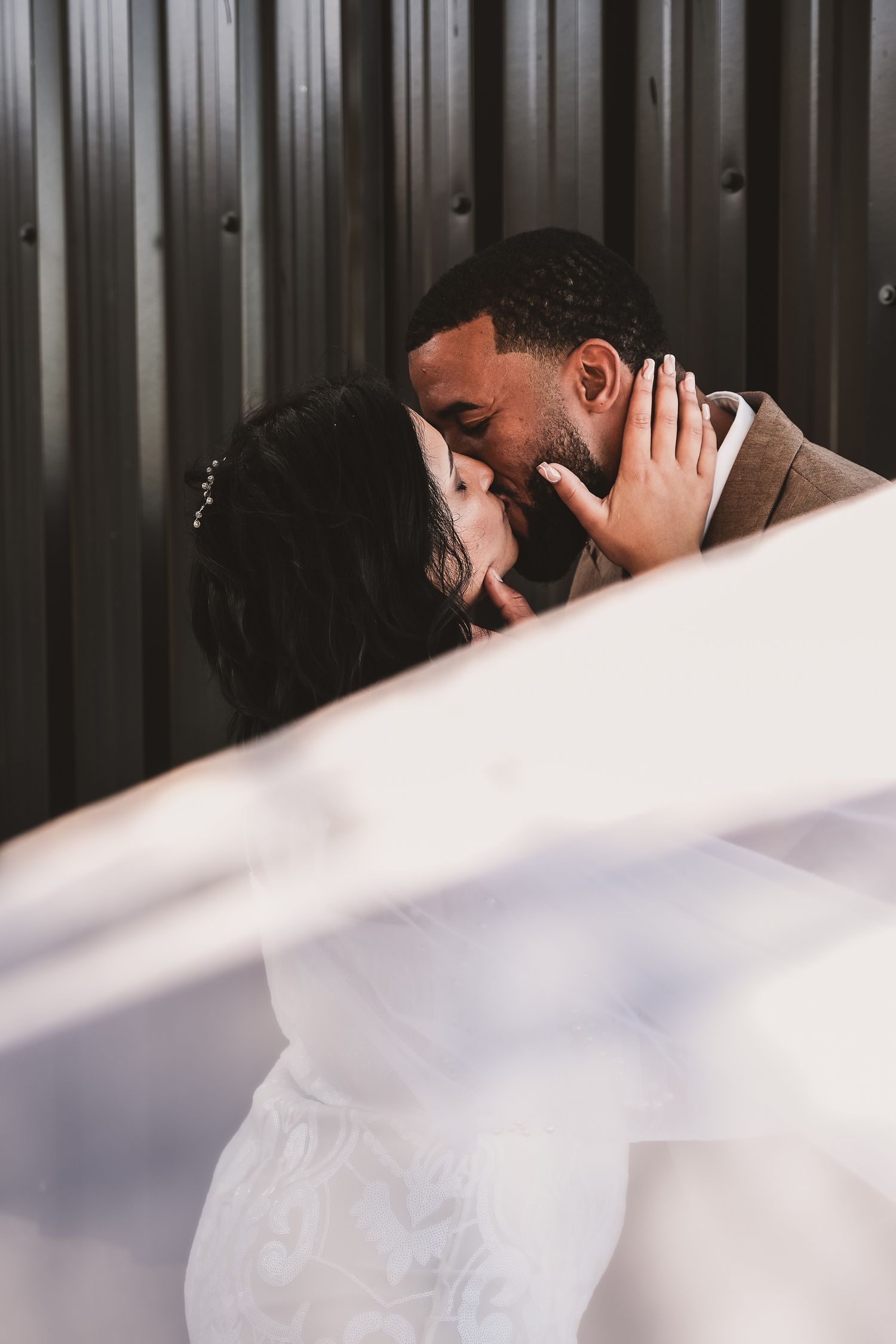 An intimate wedding moment captured against an industrial metal wall backdrop.