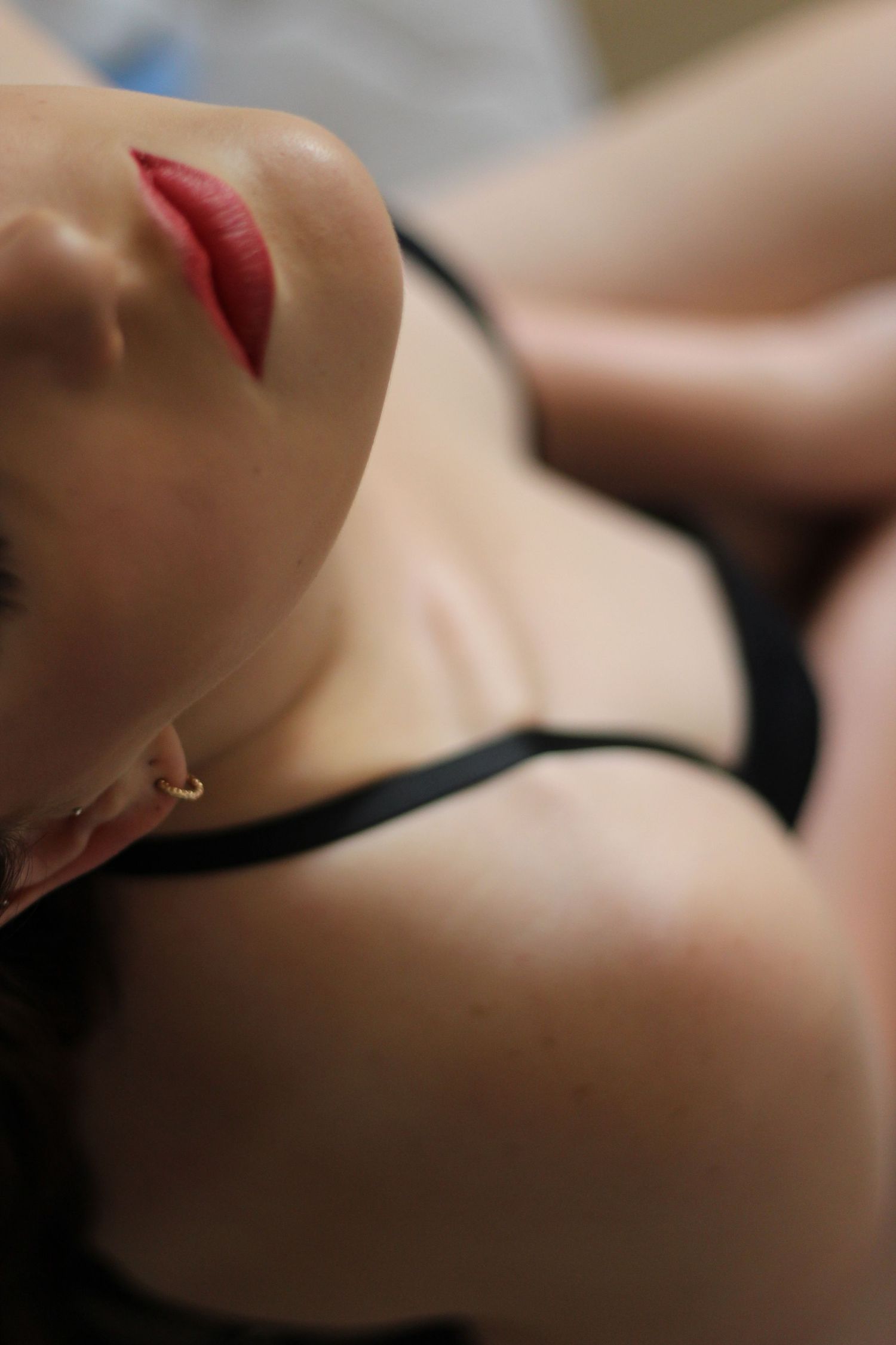 Close-up artistic portrait focusing on red lipstick and black strap.