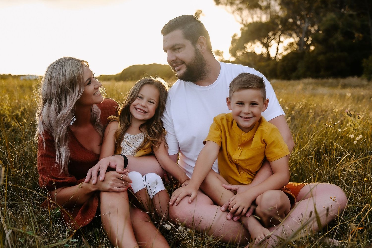 A happy family sharing a candid moment together in a sunlit field.