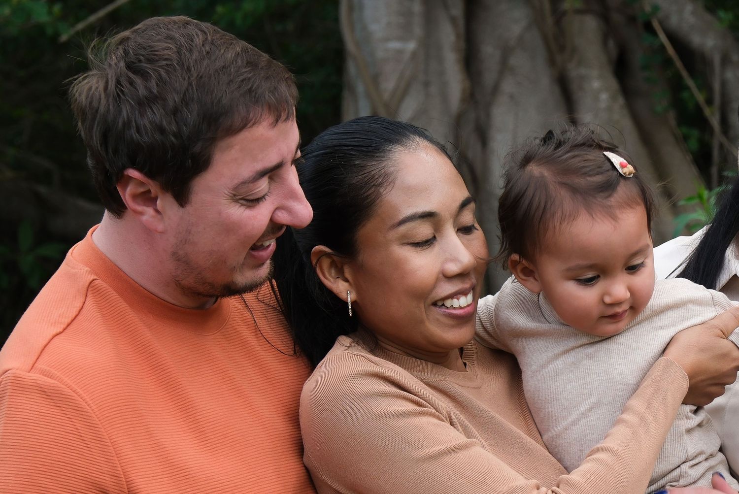 A family of three sharing an intimate moment outdoors.