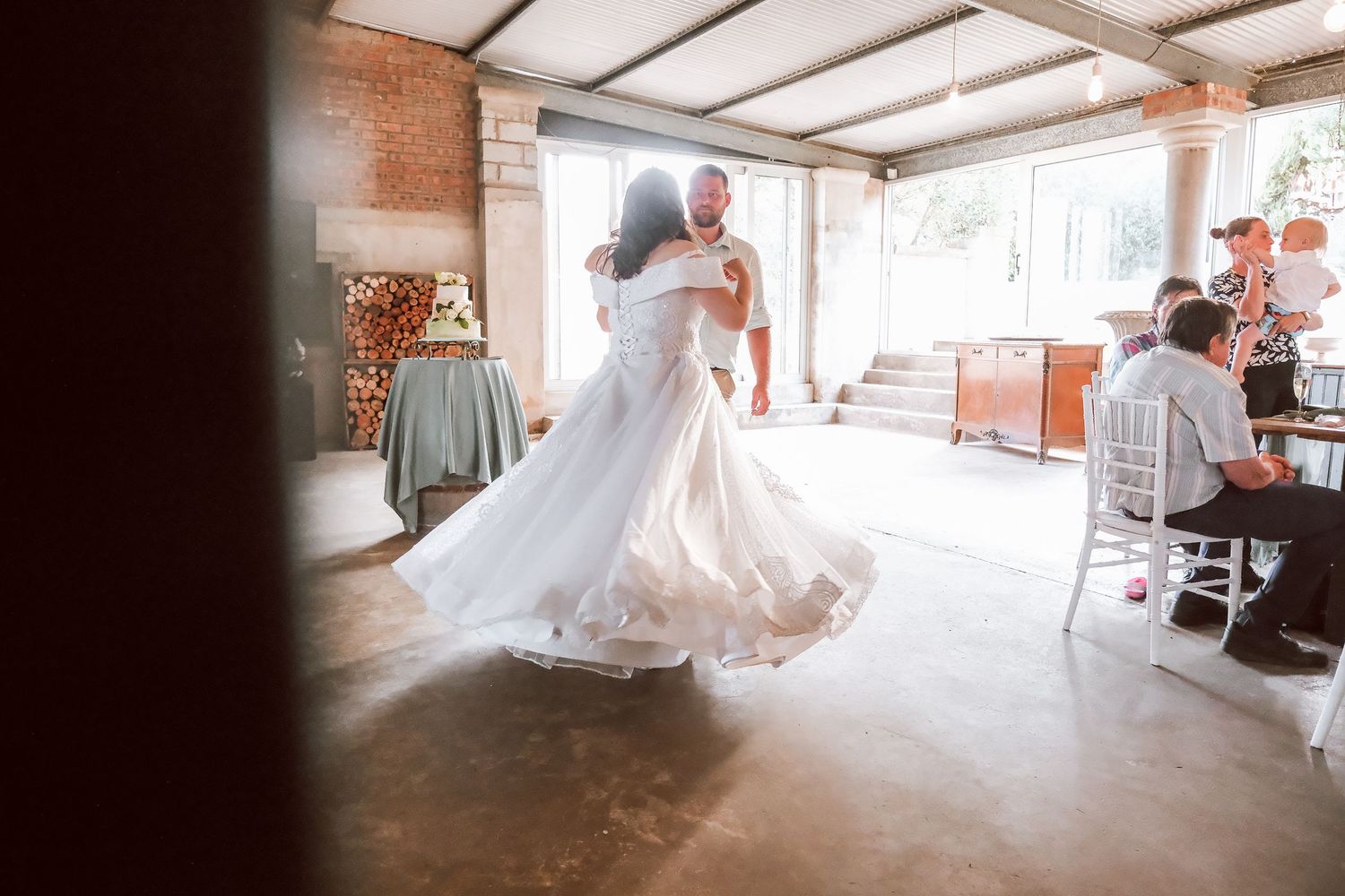 A bride twirls in her white dress inside a rustic venue.