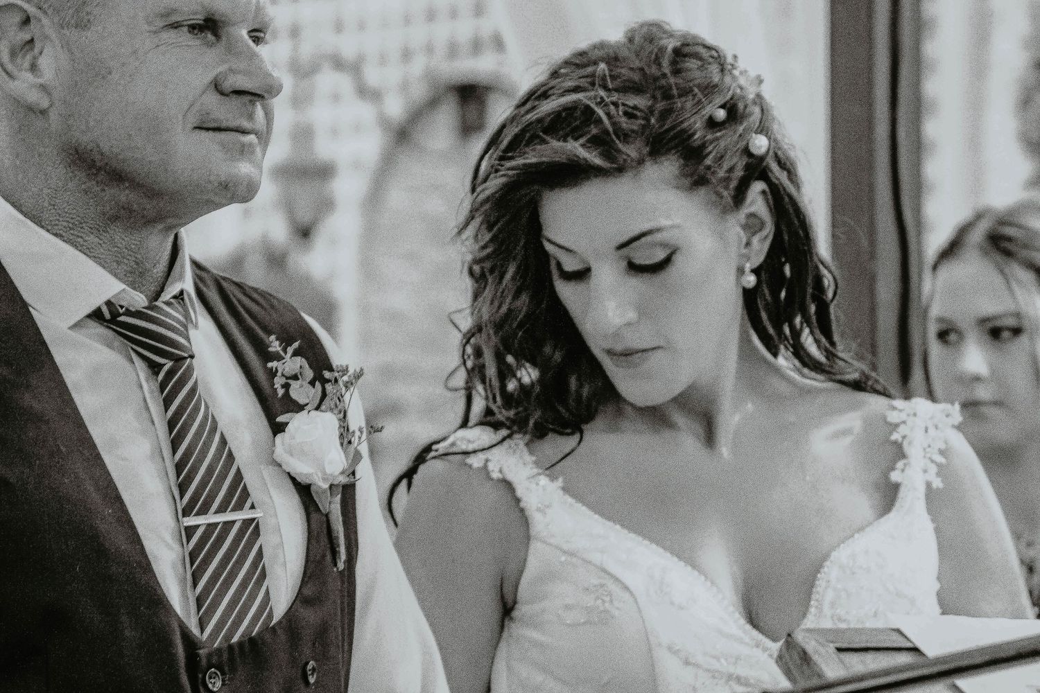 A black and white wedding portrait shows a couple in formal attire during their ceremony.