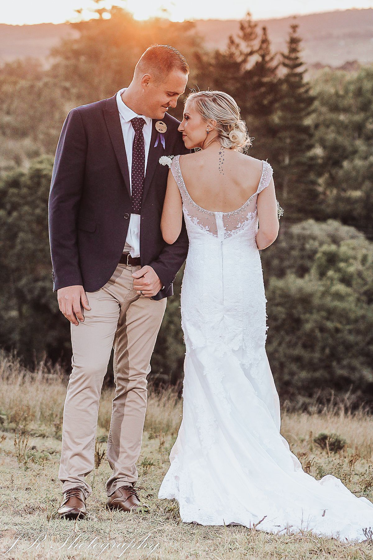 Sunset wedding portrait showing back detail of bride's lace dress.