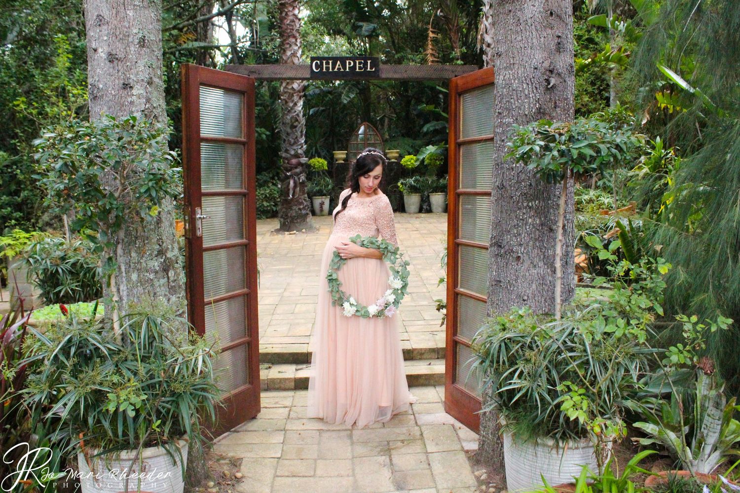 Romantic garden scene with a decorated archway entry and floral wreath on display.
