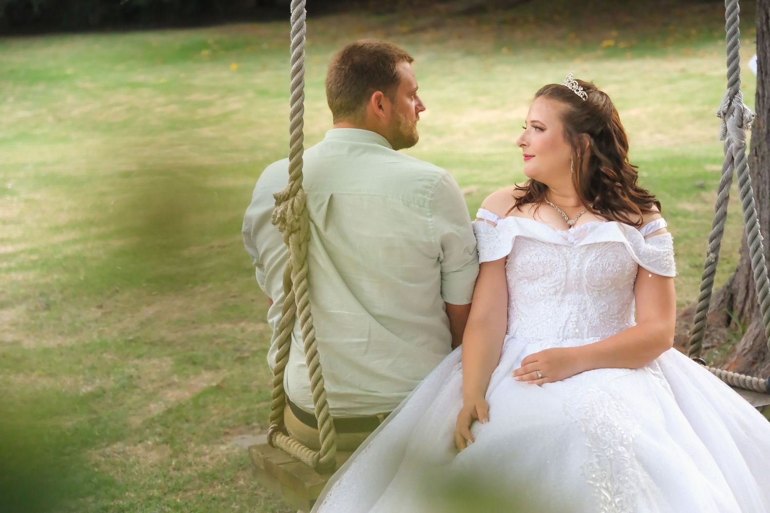 Wedding couple sharing romantic moment on rope swing outdoors.