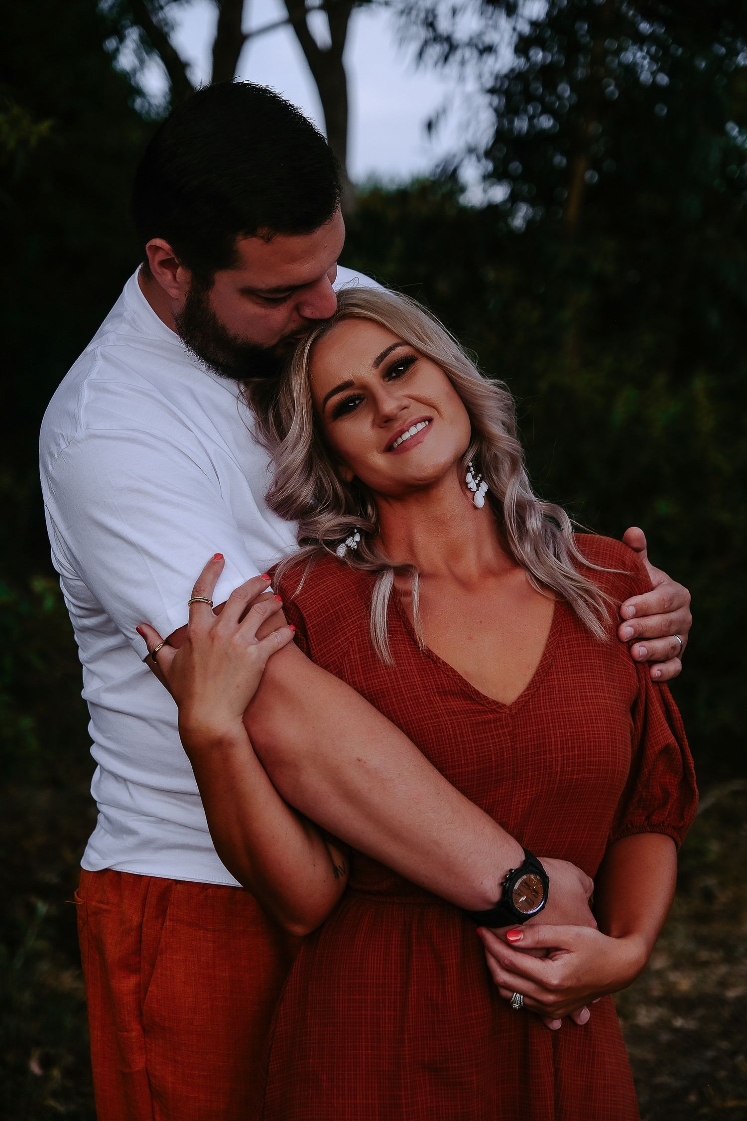Couple in coordinating red and white outfits embrace at sunset.