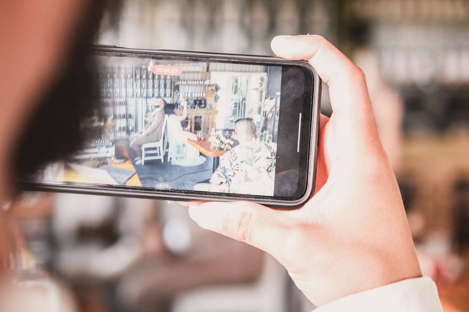 Someone holding a smartphone taking a photo of products on display in a cafe or store.