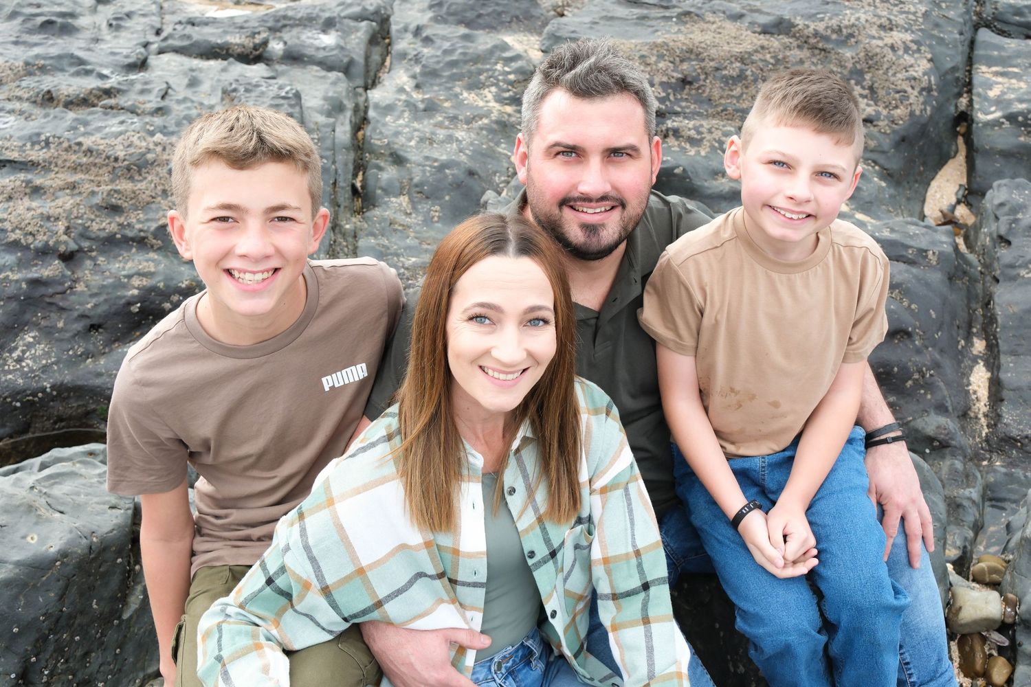 Small group posing together against rocky coastal backdrop during cloudy day.