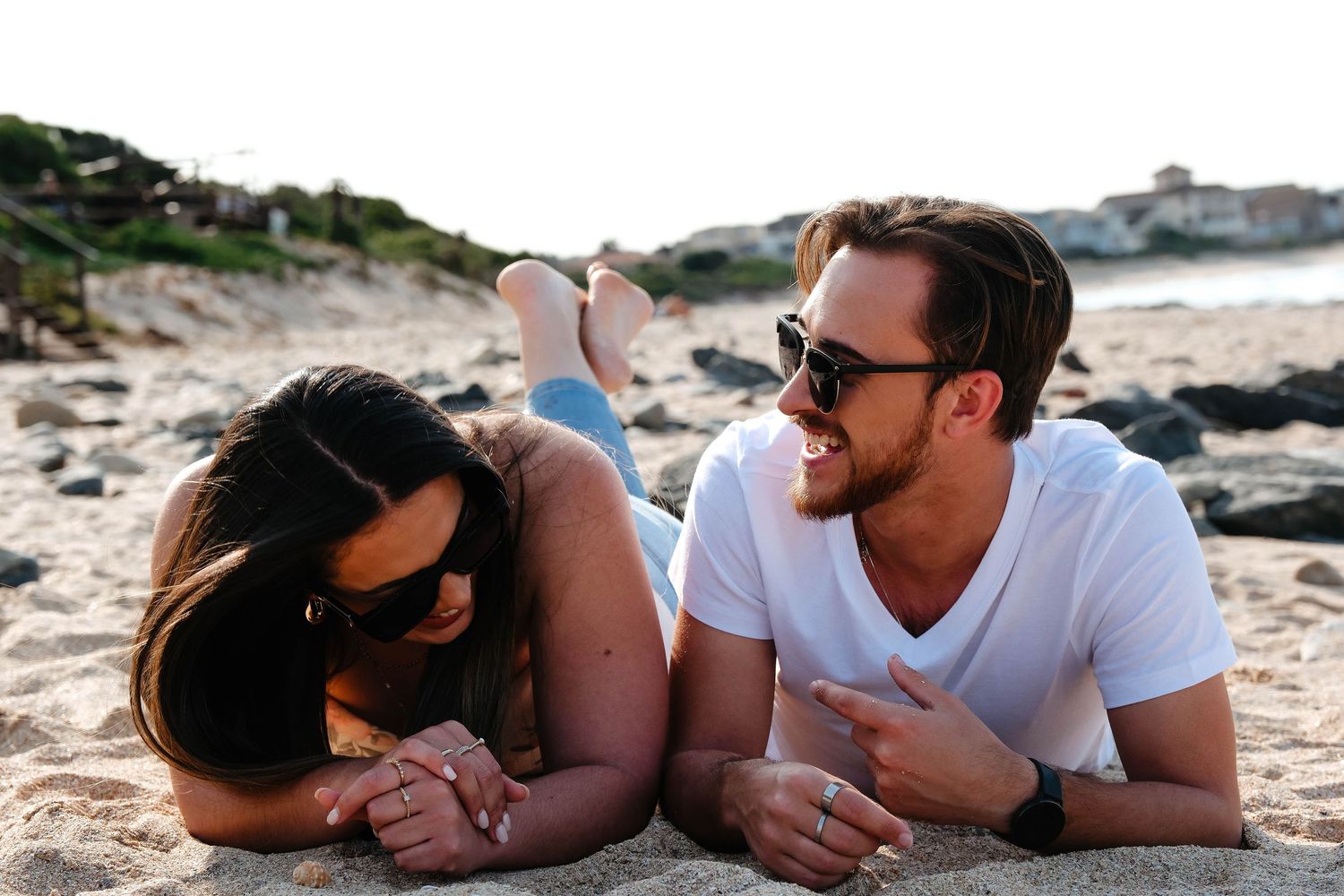 A couple laying together on a sandy beach enjoying a relaxed moment.