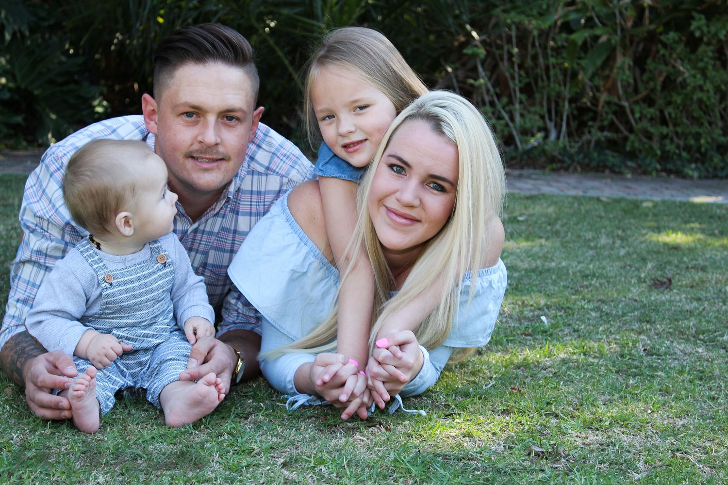 Family lying together on grass during outdoor photo session.