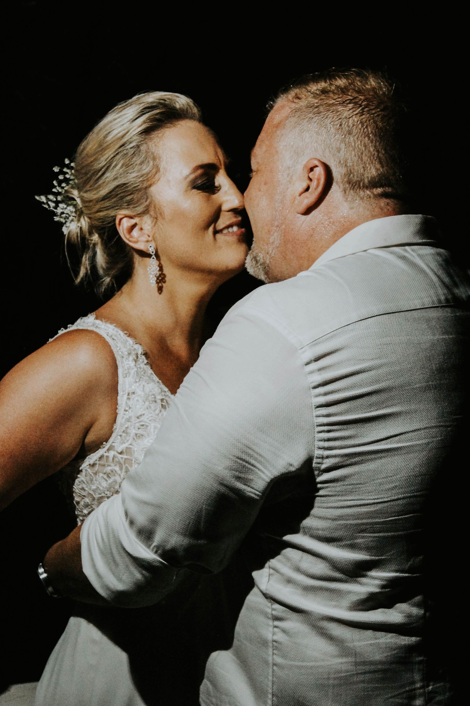 Elegantly dressed couple embraces in intimate black and white wedding portrait.