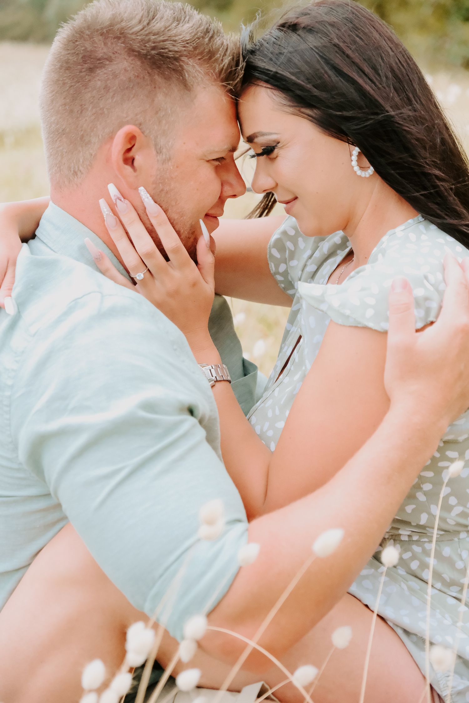 Close-up of romantic moment between couple in meadow with soft bokeh lighting.