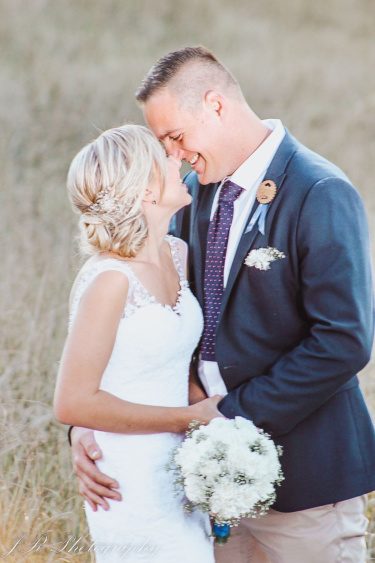 Joyful wedding portrait with white bouquet and elegant attire during outdoor session.