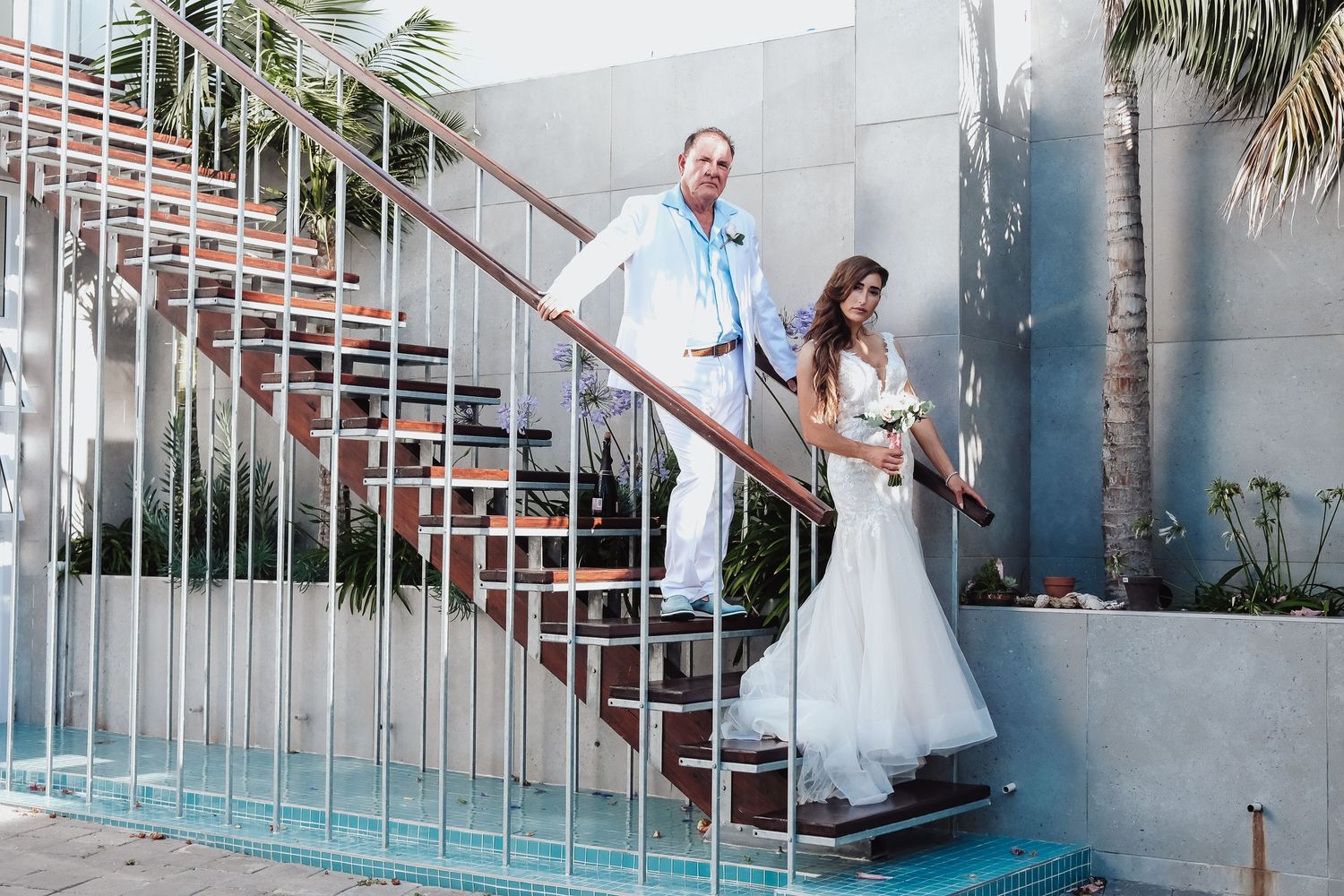 Wedding ceremony in clear tent with chandelier and white ceremony arch surrounded by guests.
