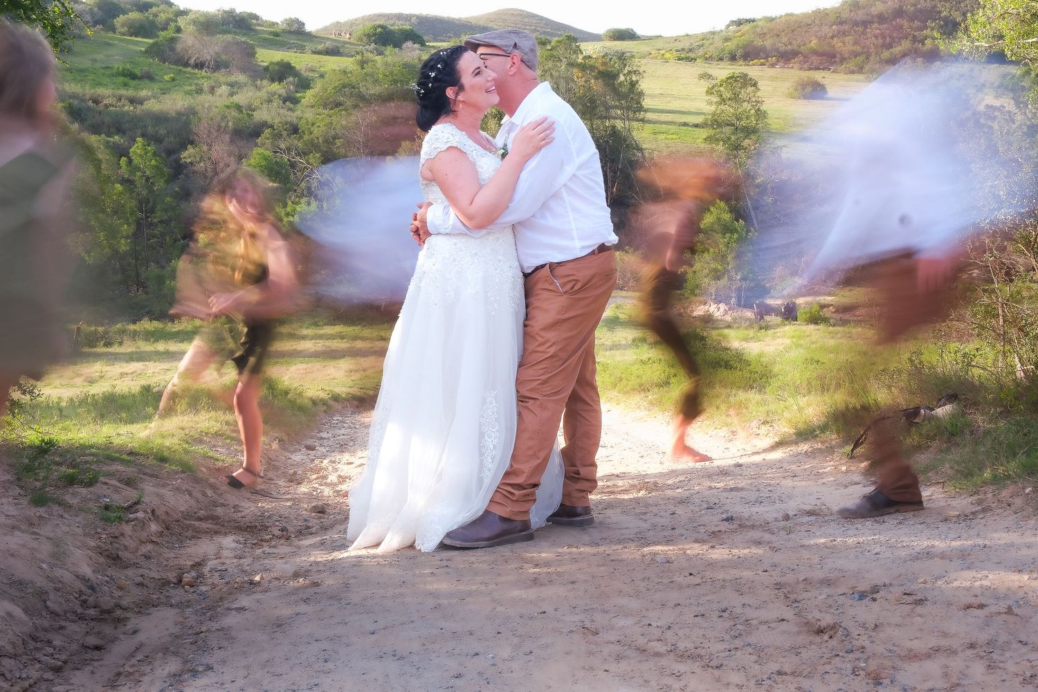 Couple dancing in white dress and casual attire with motion blur effect outdoors.
